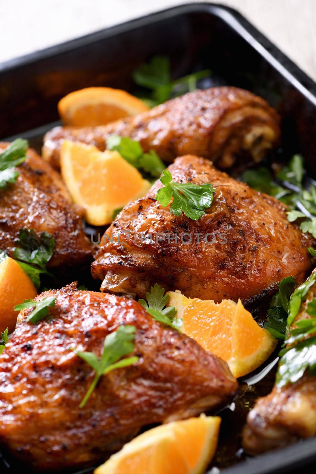 appetizing slices of baked chicken with crispy fried crust and oranges in a baking sheet