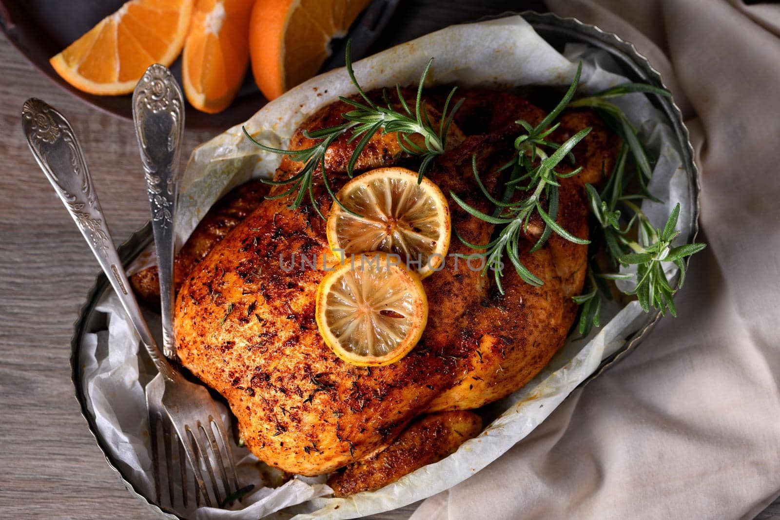 Baked whole chicken in spices with crispy appetizing fried crust in a tray, dark moody  