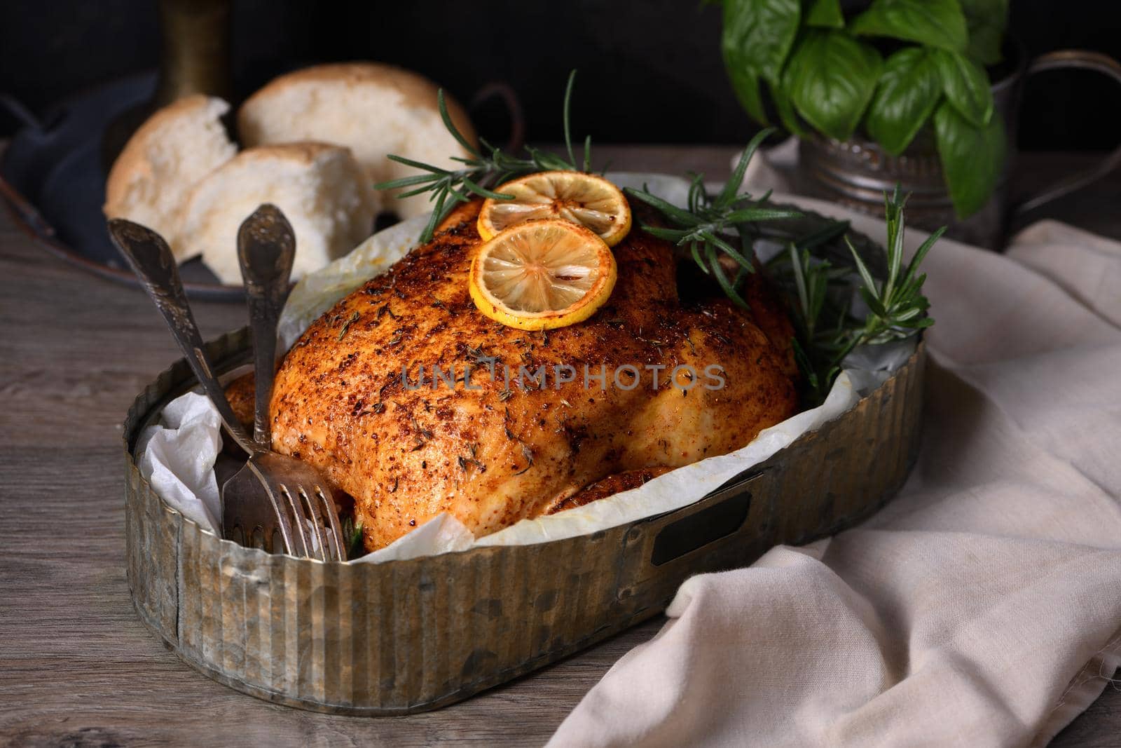 Baked whole chicken in spices with crispy appetizing fried crust in a tray, dark moody  