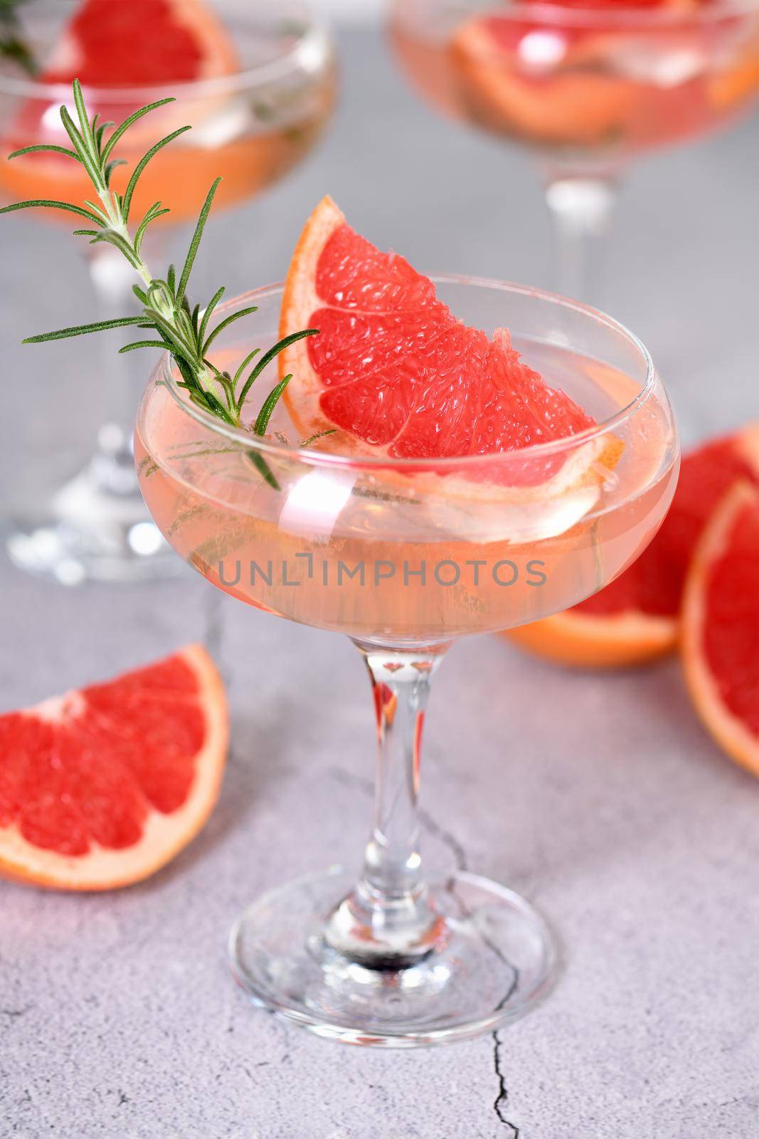 Goblet of sparkling wine with a slice of grapefruit and a sprig of rosemary