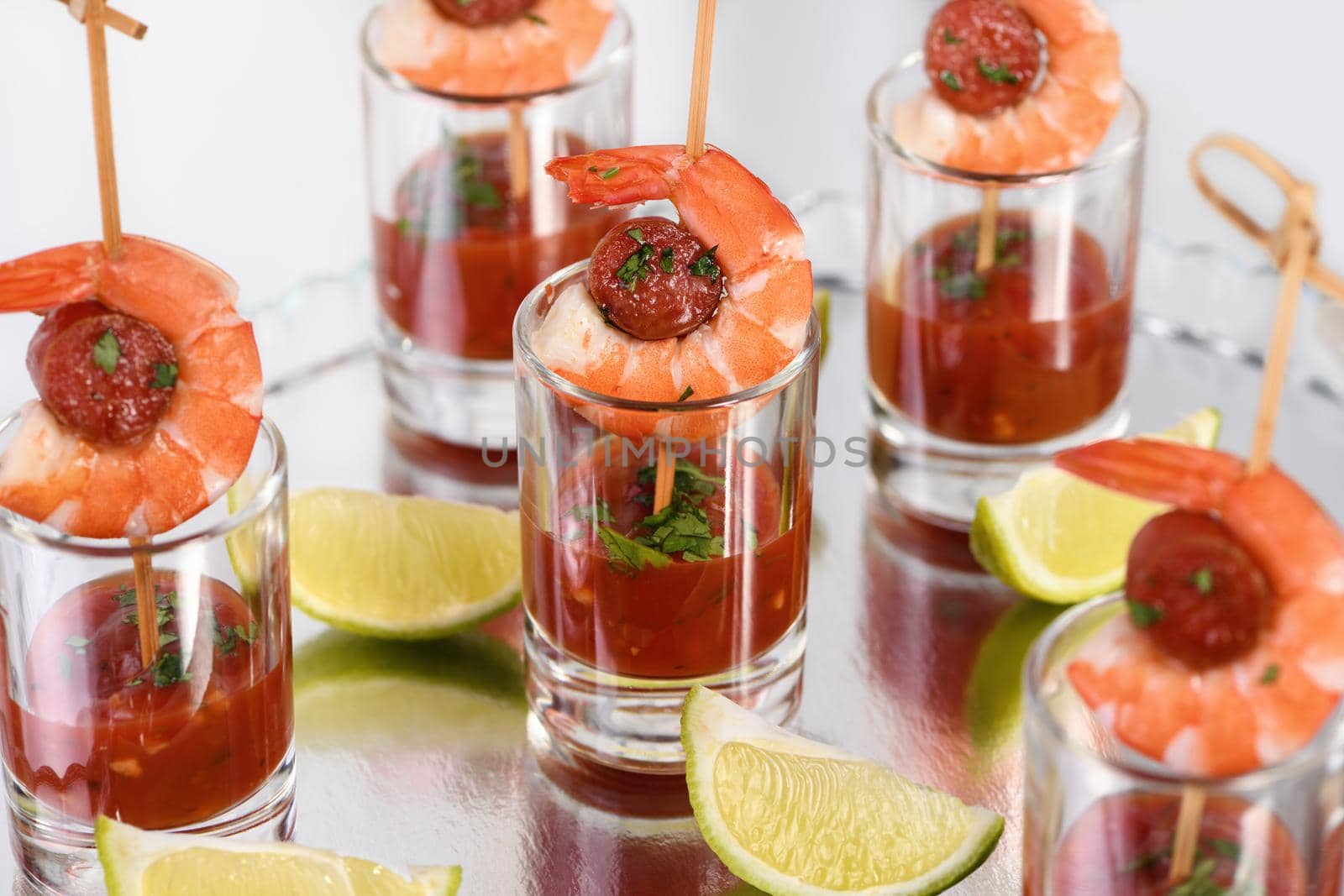 Appetizer of shish kebab with shrimps and chorizo sausages with barbecue sauce in a glass