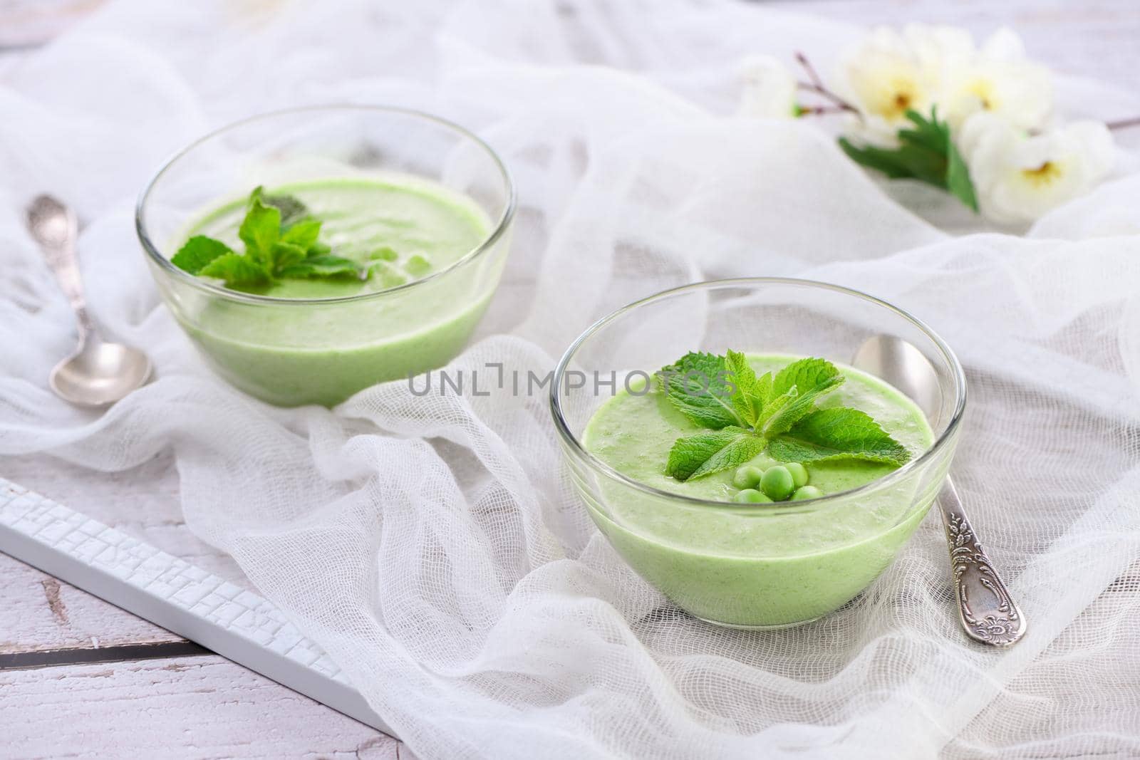 Chilled green pea puree soup with tender milk cream and refreshing mint