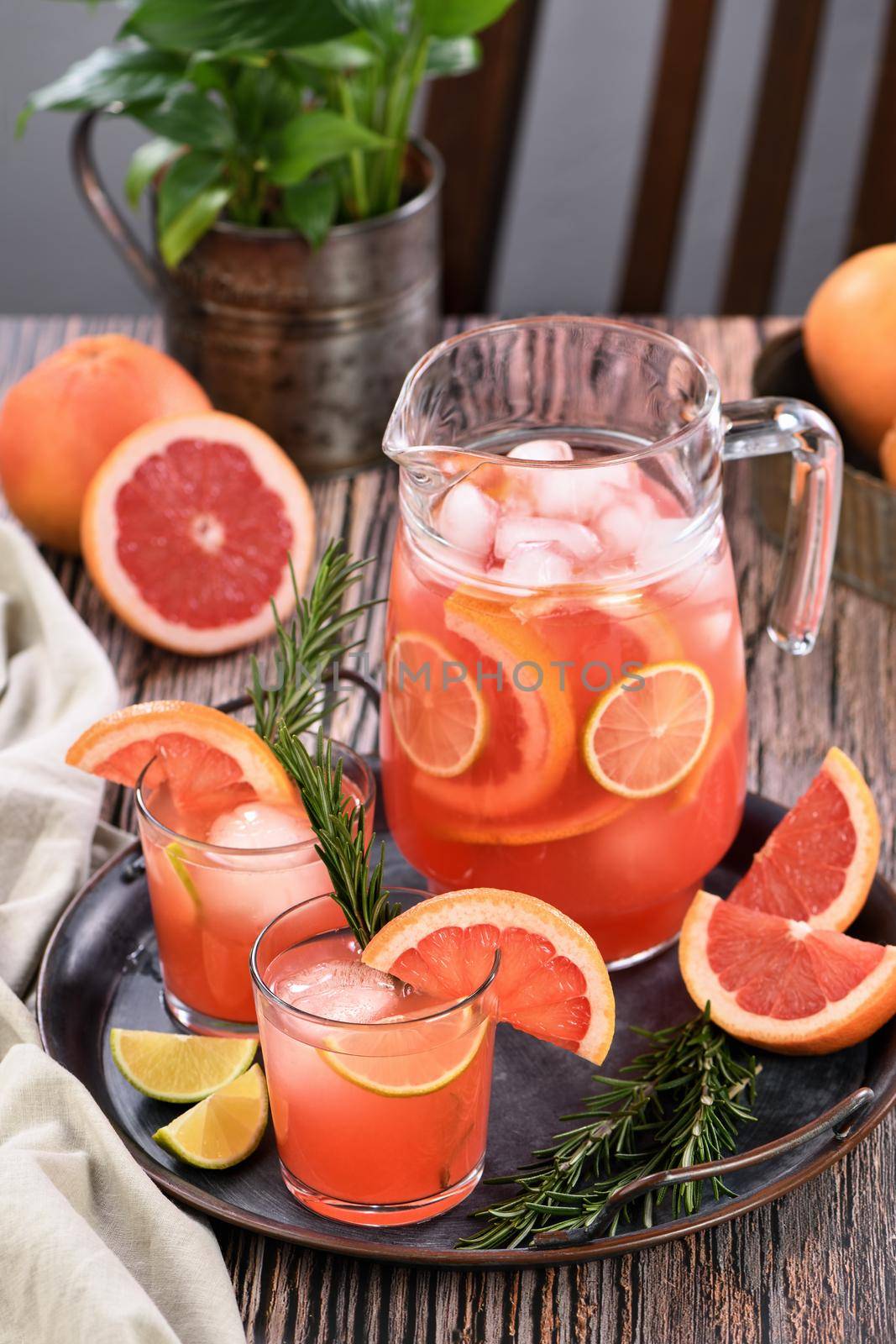 Fresh grapefruit cocktail. Fresh summer cocktail with grapefruit, lime, sprig of rosemary and ice cubes.