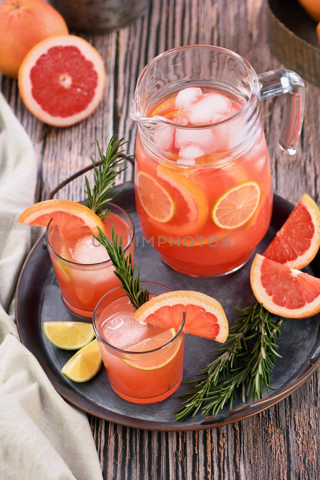 Fresh grapefruit cocktail. Fresh summer cocktail with grapefruit, lime, sprig of rosemary and ice cubes.