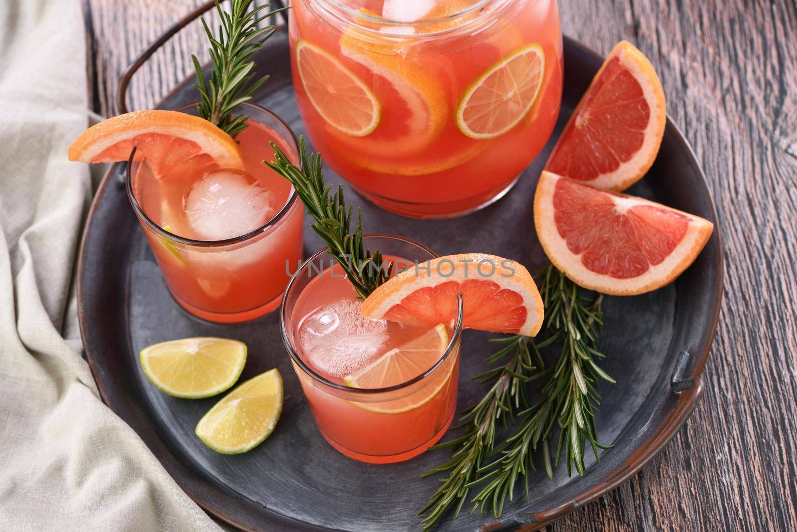 Fresh grapefruit cocktail. Fresh summer cocktail with grapefruit, lime, sprig of rosemary and ice cubes.