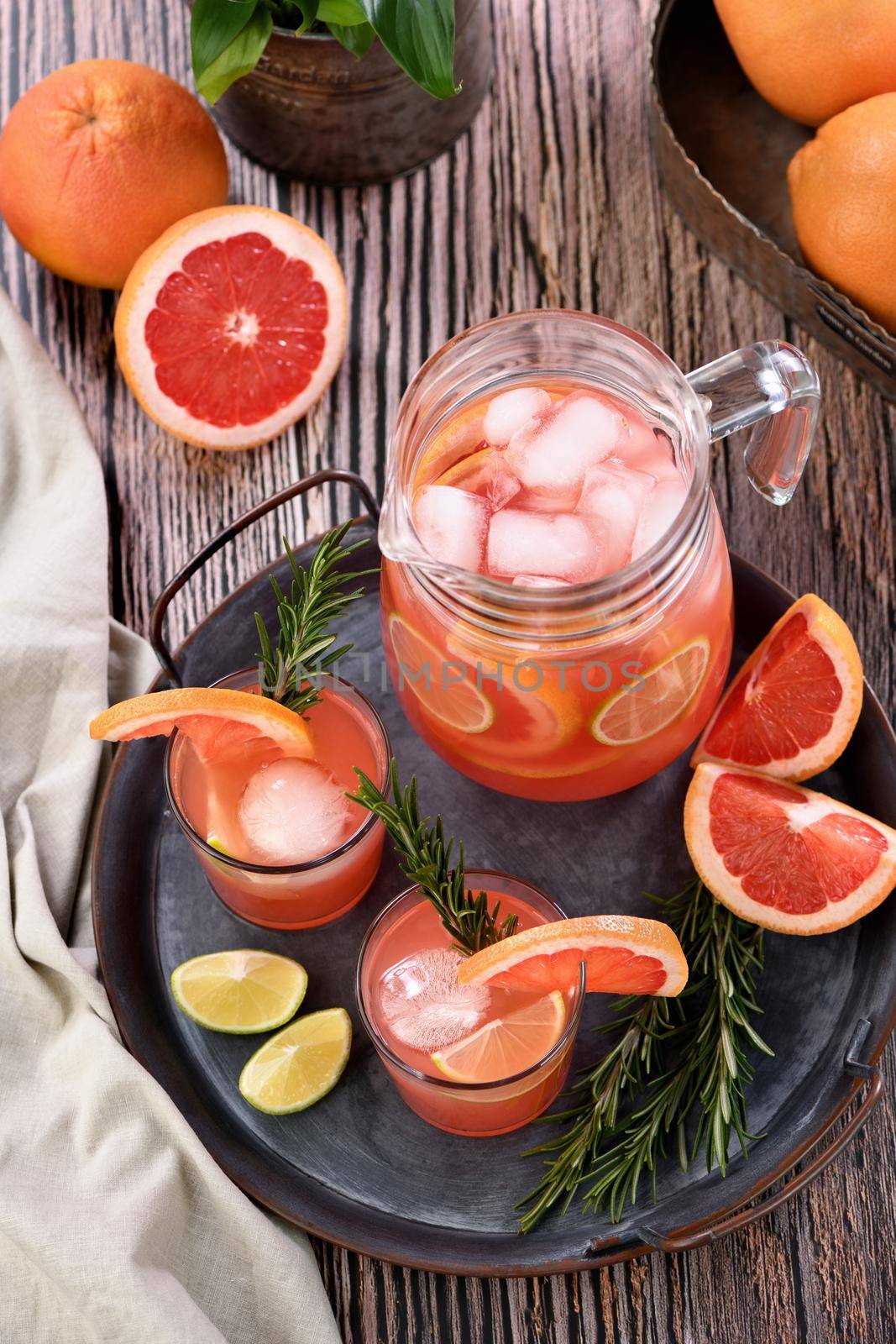 Fresh grapefruit cocktail. Fresh summer cocktail with grapefruit, lime, sprig of rosemary and ice cubes.