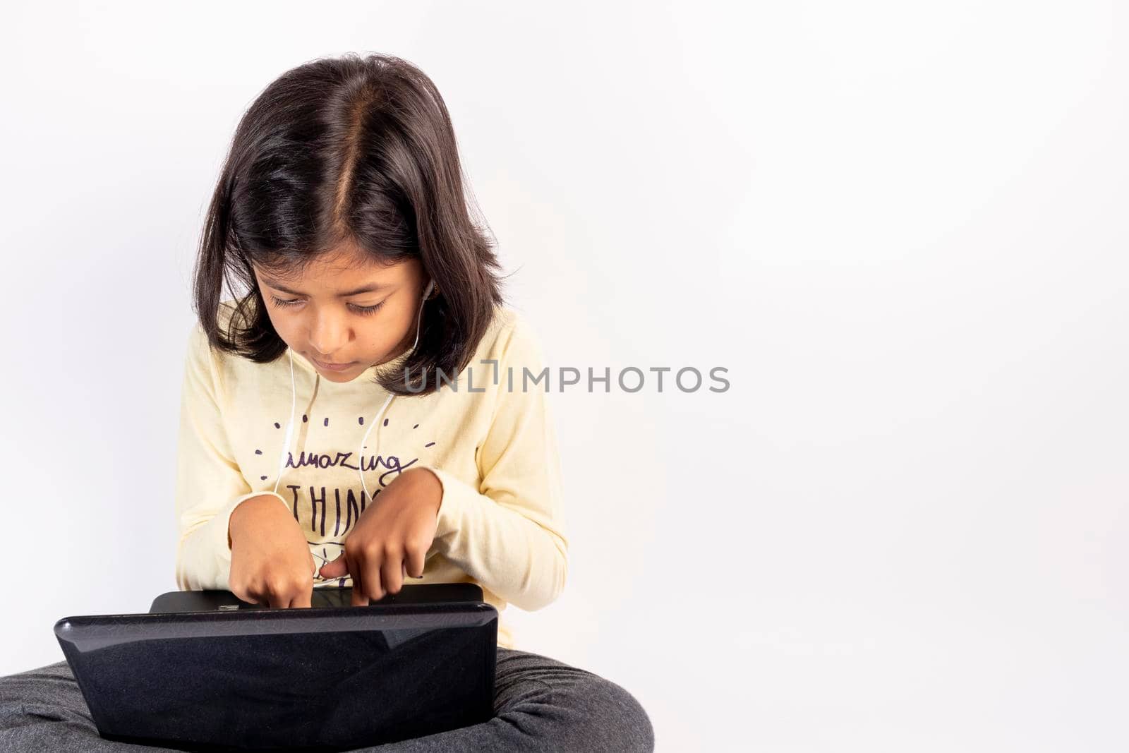 Cute little girl is using her notebook and headphones