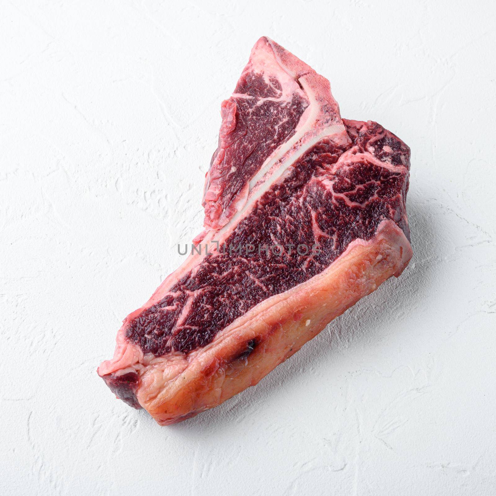 Dry-aged Raw T-bone or porterhouse beef marbled meat prime steak set, on white stone background, square format
