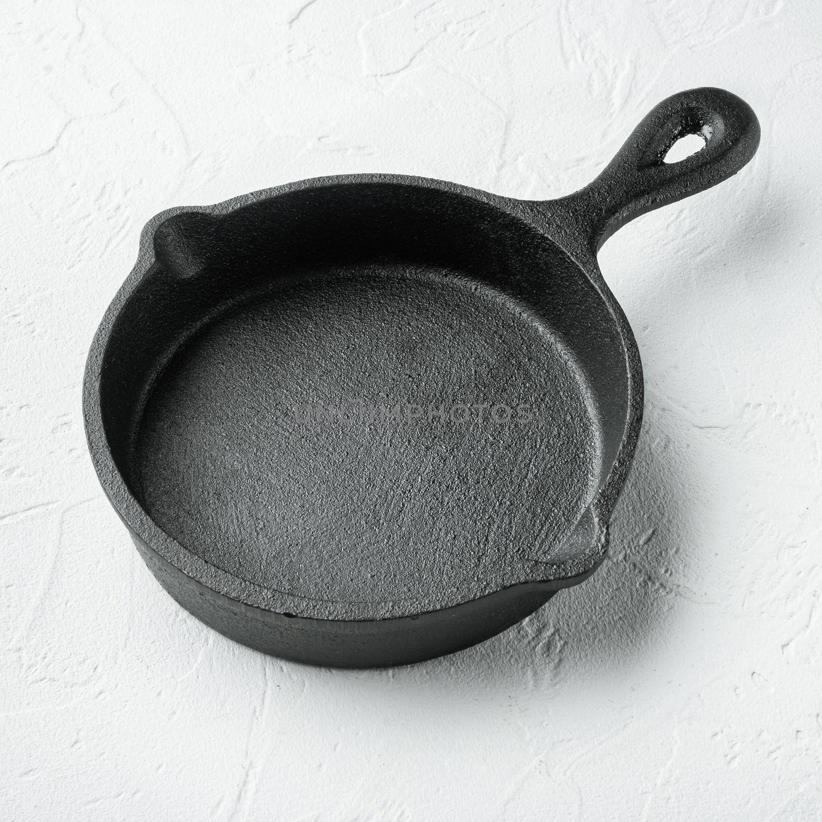 Kitchenware frying cast iron pan, on white stone surface, square format by Ilianesolenyi