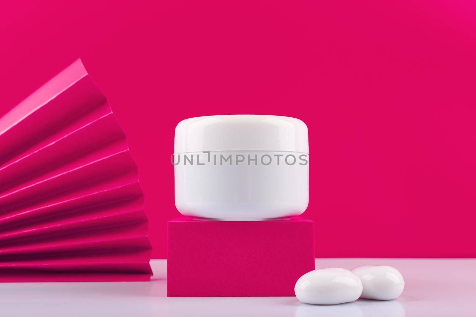Close up of white cosmetic jar with cream, mask, balm or scrub on pink podium against pink background with pink waver  by Senorina_Irina