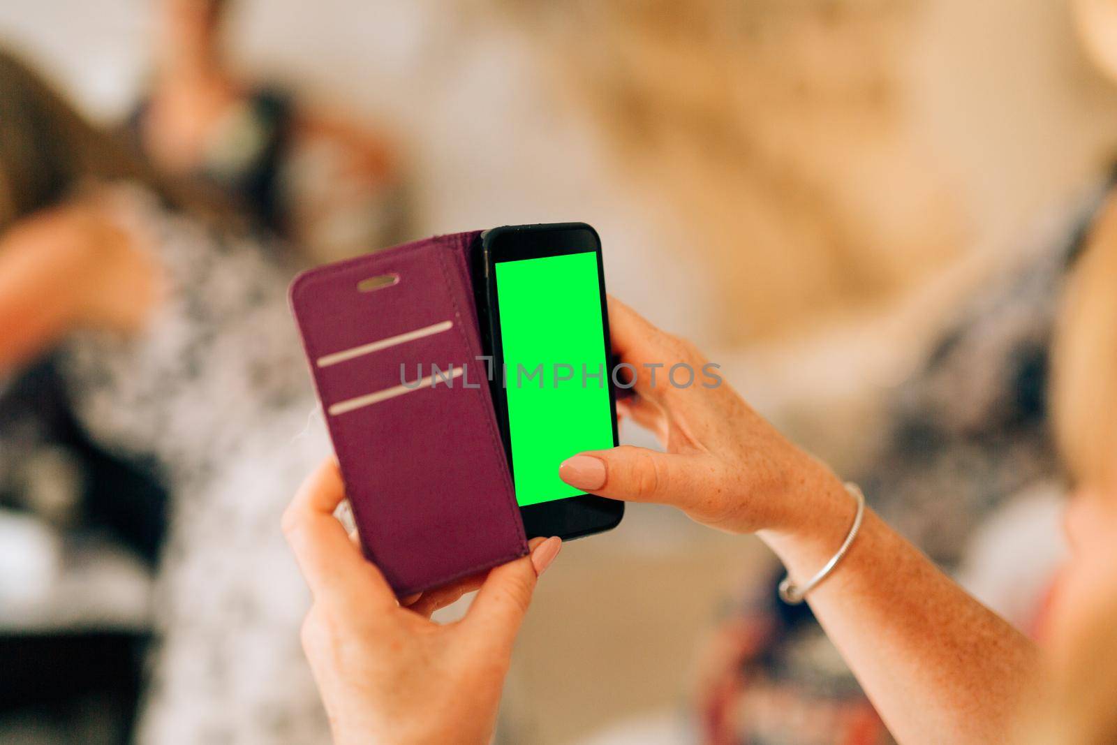 Girl holding a black smartphone with a blank screen in a leather protective case in her hands by Nadtochiy