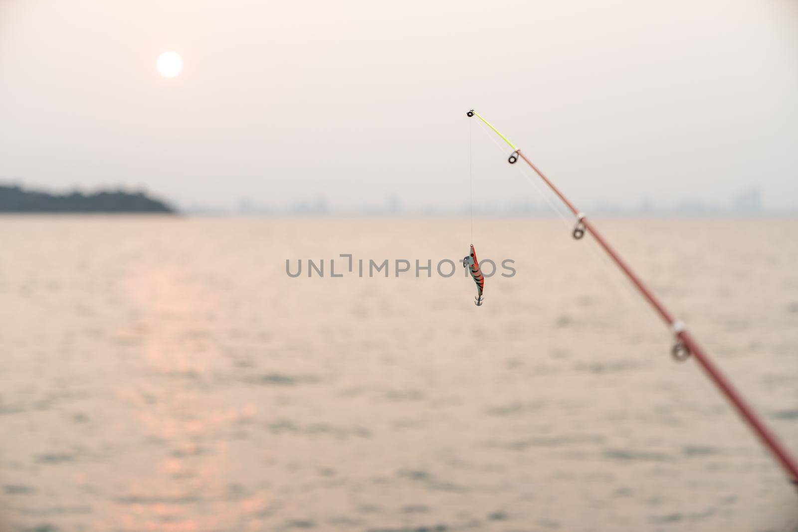 Artificial small fish on a fishing rod with sea background, fishing at sunset. by sirawit99