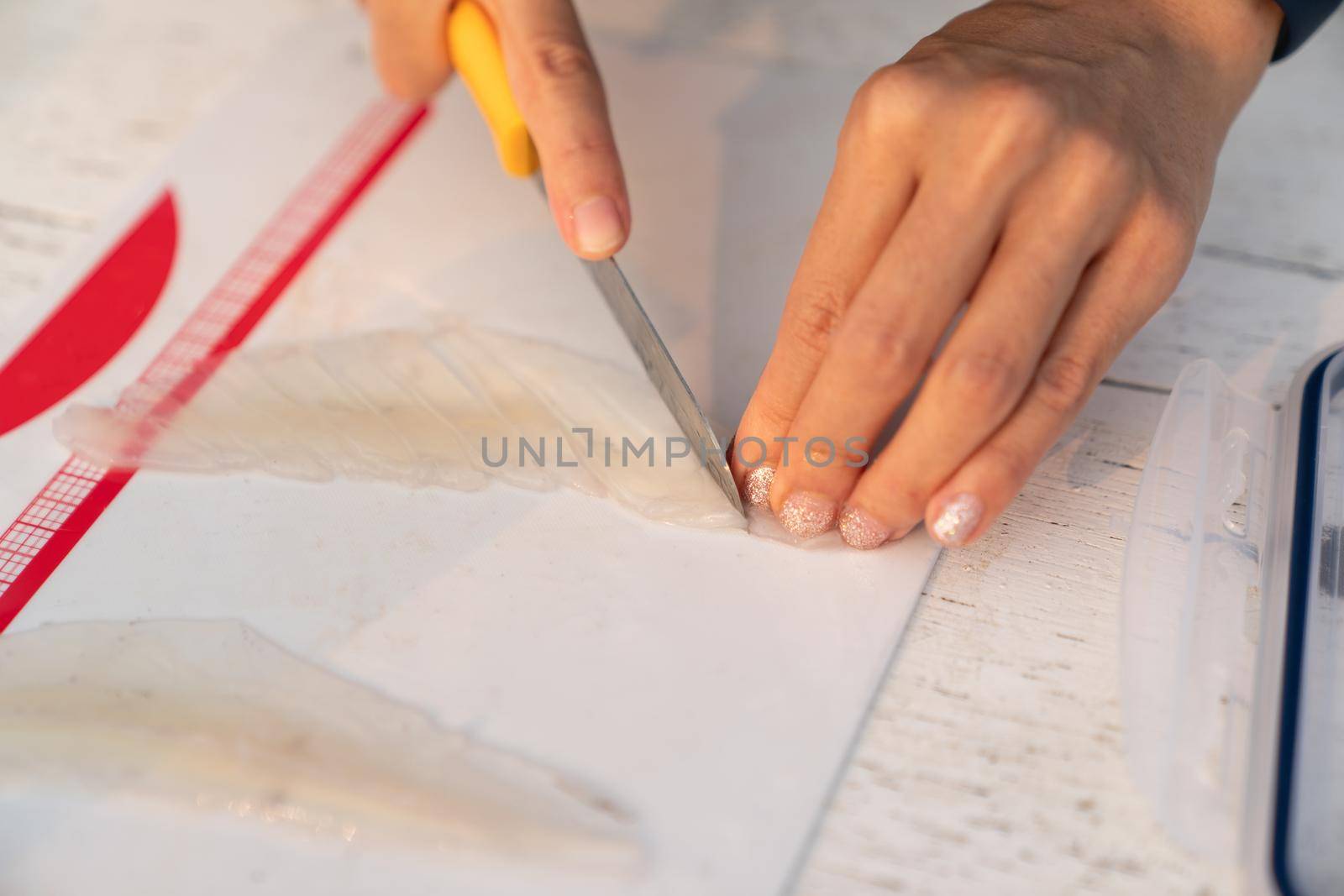 Chef preparing slicing raw squid for sushi, on cutting board.