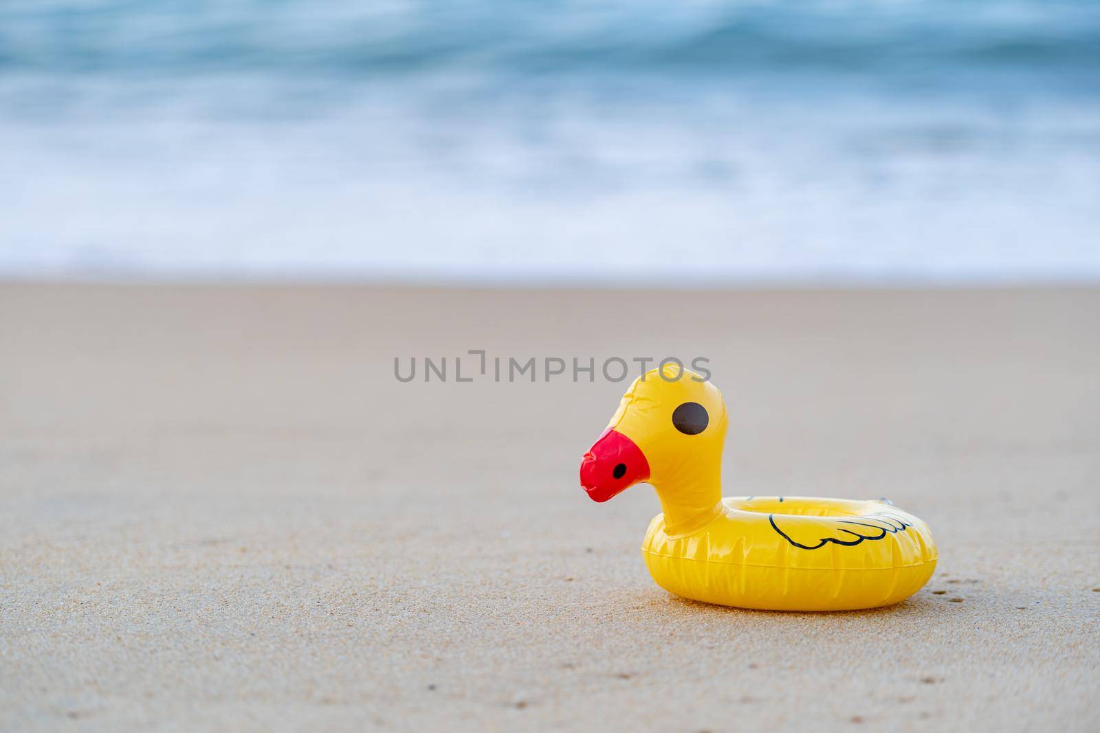 Yellow rubber duck on the seashore in the morning, sand beach.