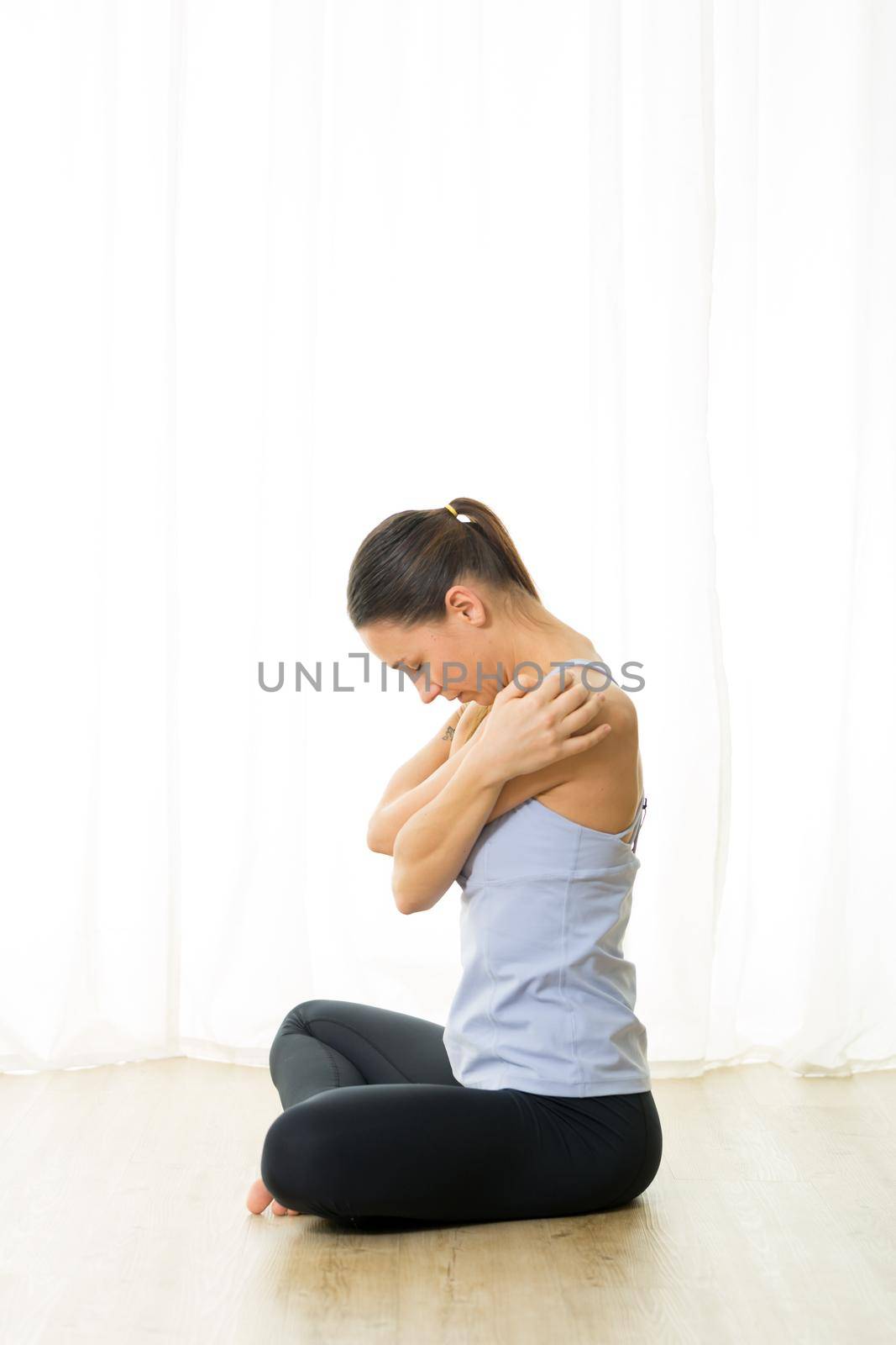 Portrait of gorgeous active sporty young woman practicing breathing exercises in yoga studio. Healthy active lifestyle, working out indoors in gym.