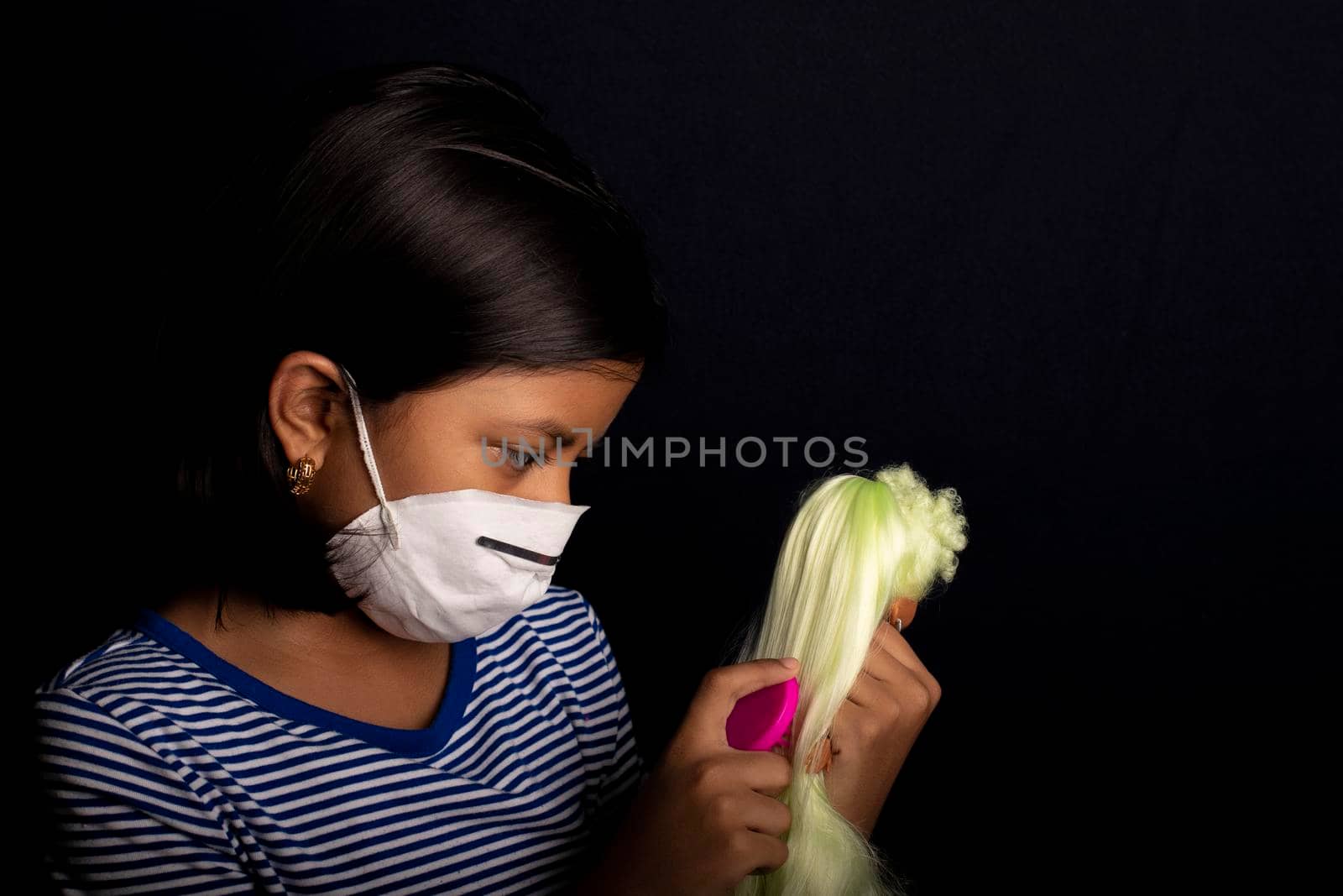 Little girl with medical face mask, playing with her doll