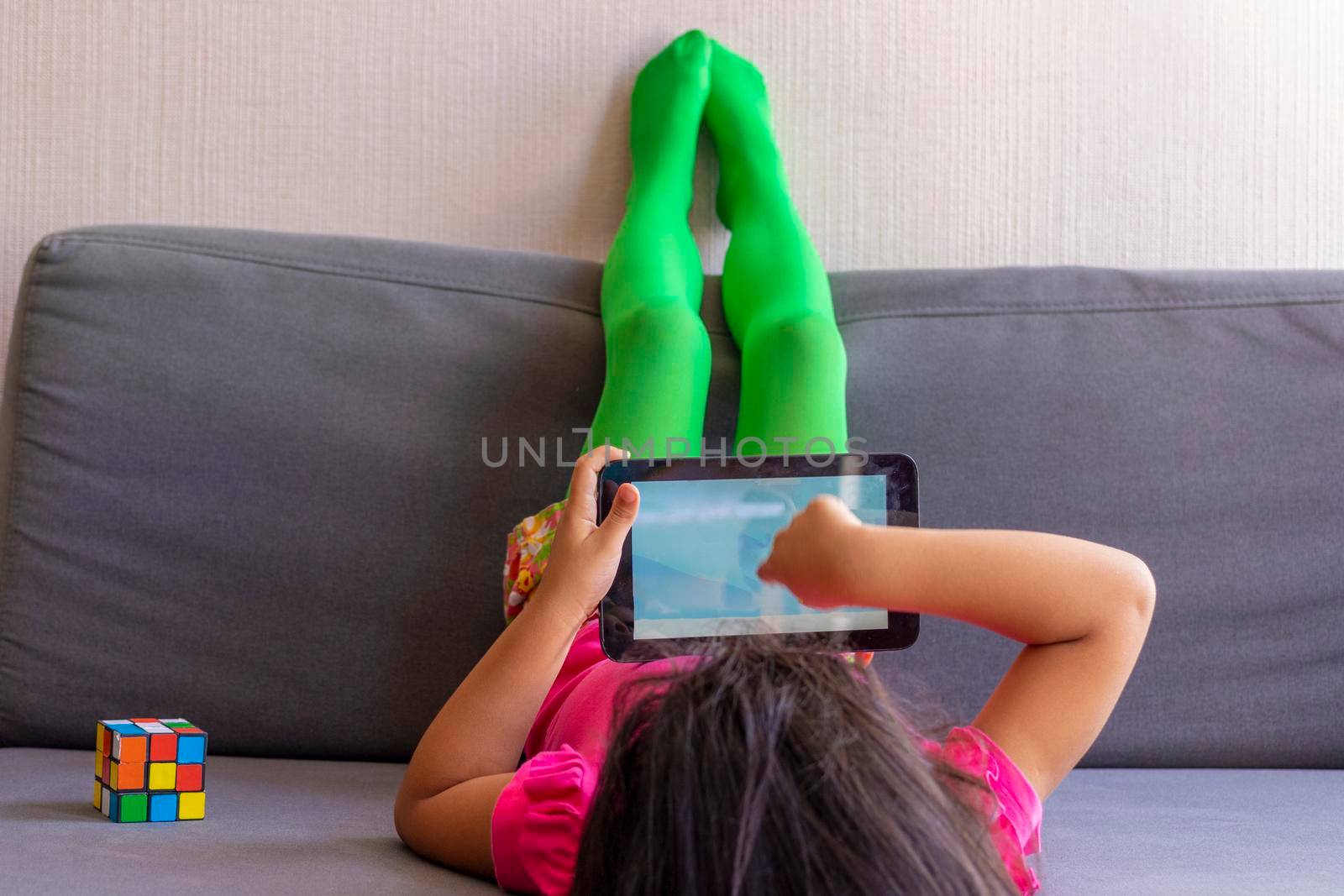 Little girl playing with her tablet lying on the sofa by eagg13