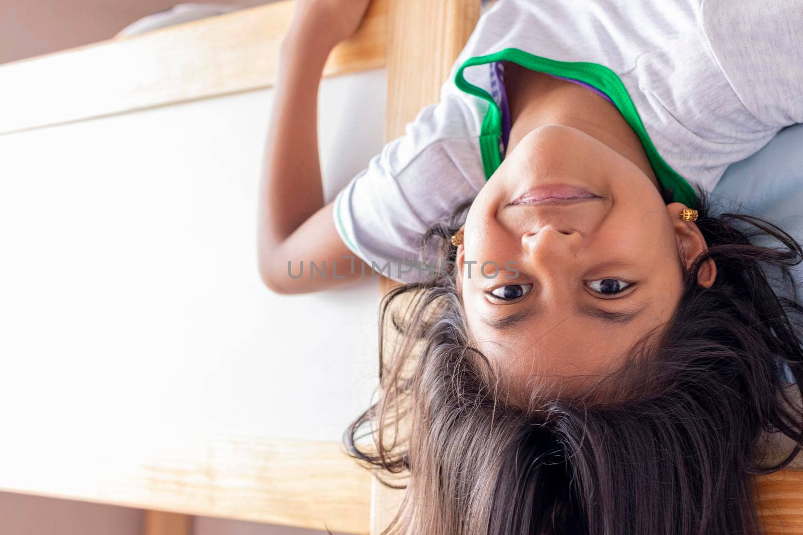 A girl is upside down looking down from the top of her bunk