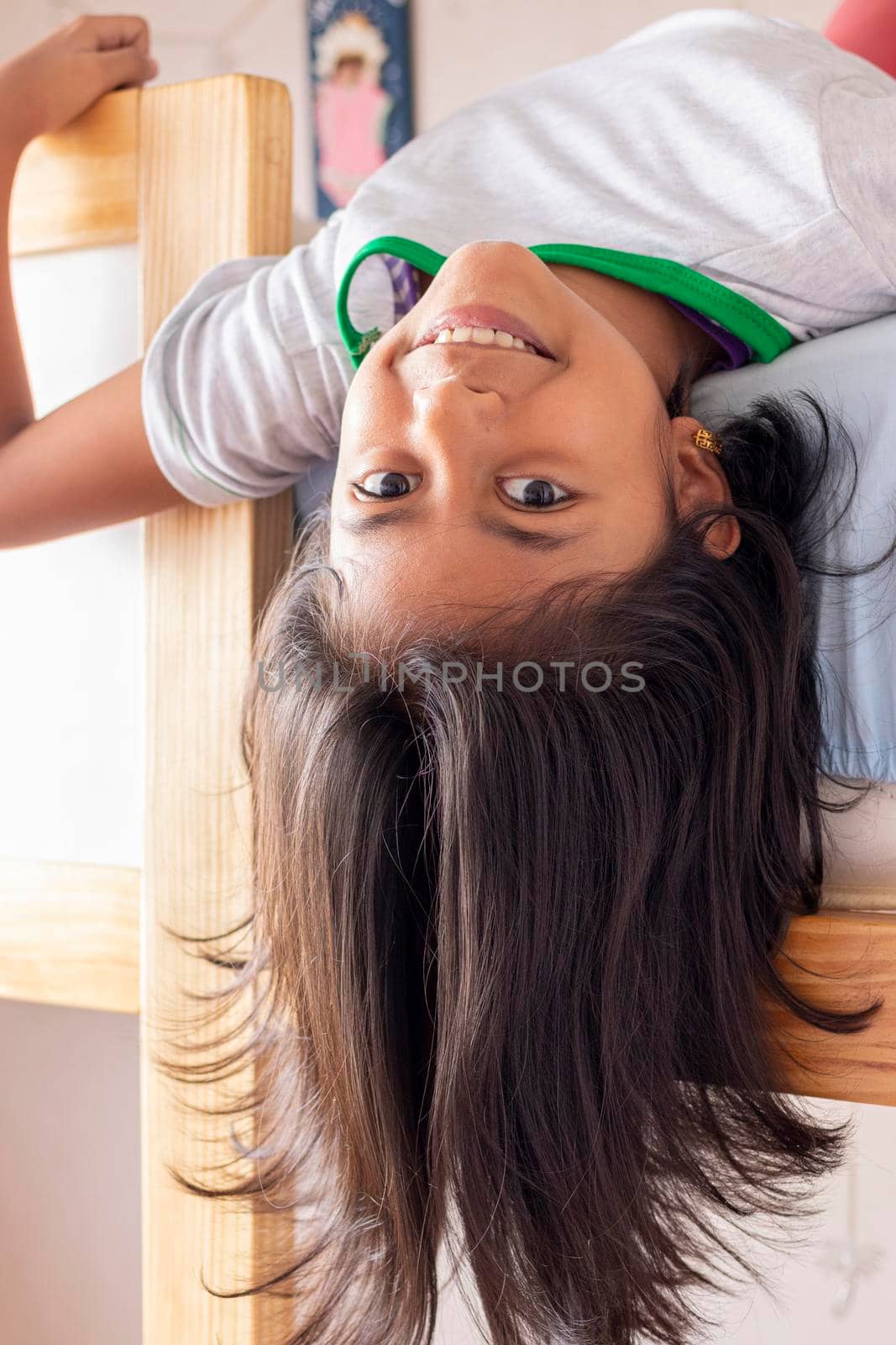 A girl is upside down looking down from the top of her bunk