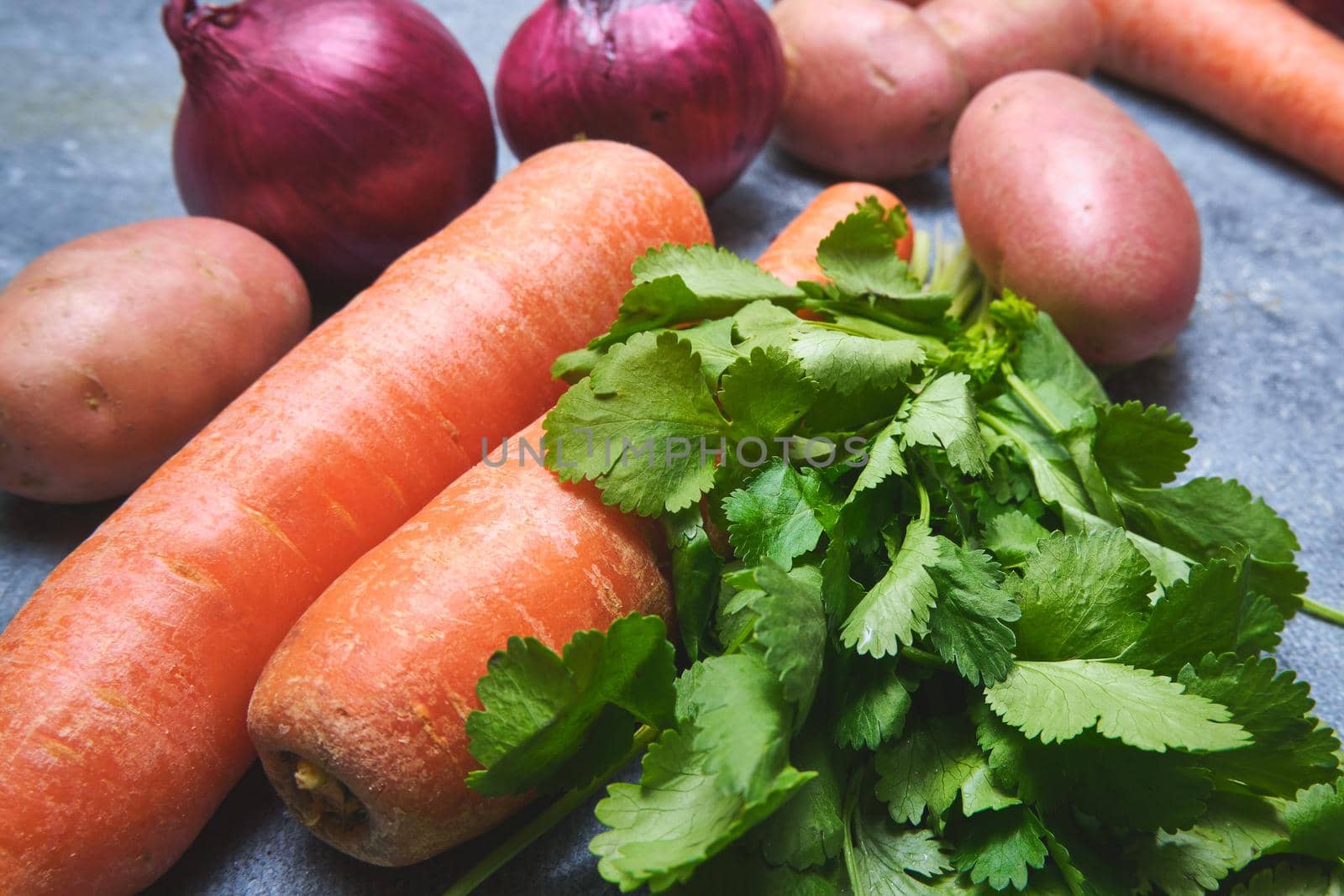 Turnip, cilantro, potatoes, carrots and red onions on a dark background