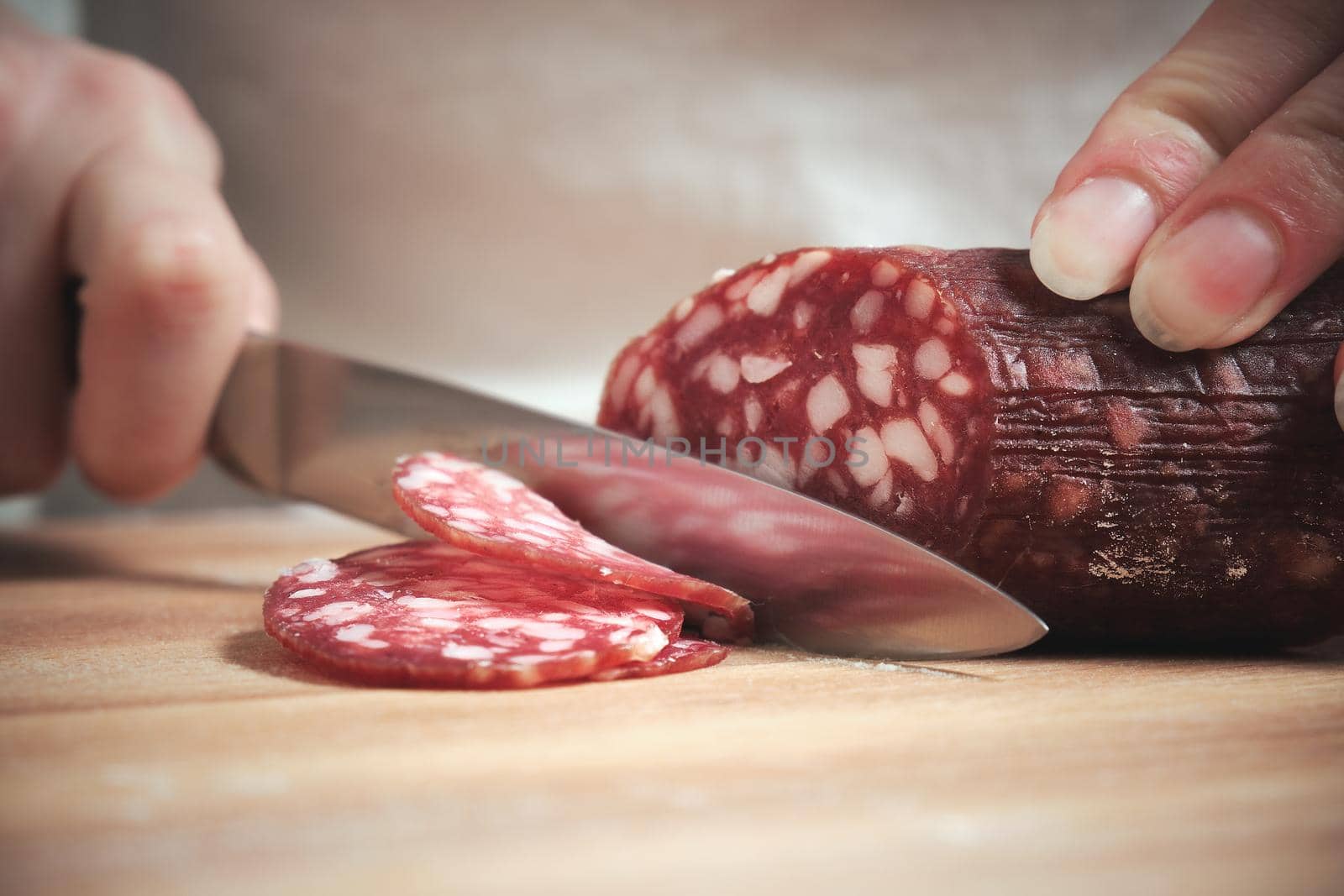 The knife cuts the smoked sausage into pieces