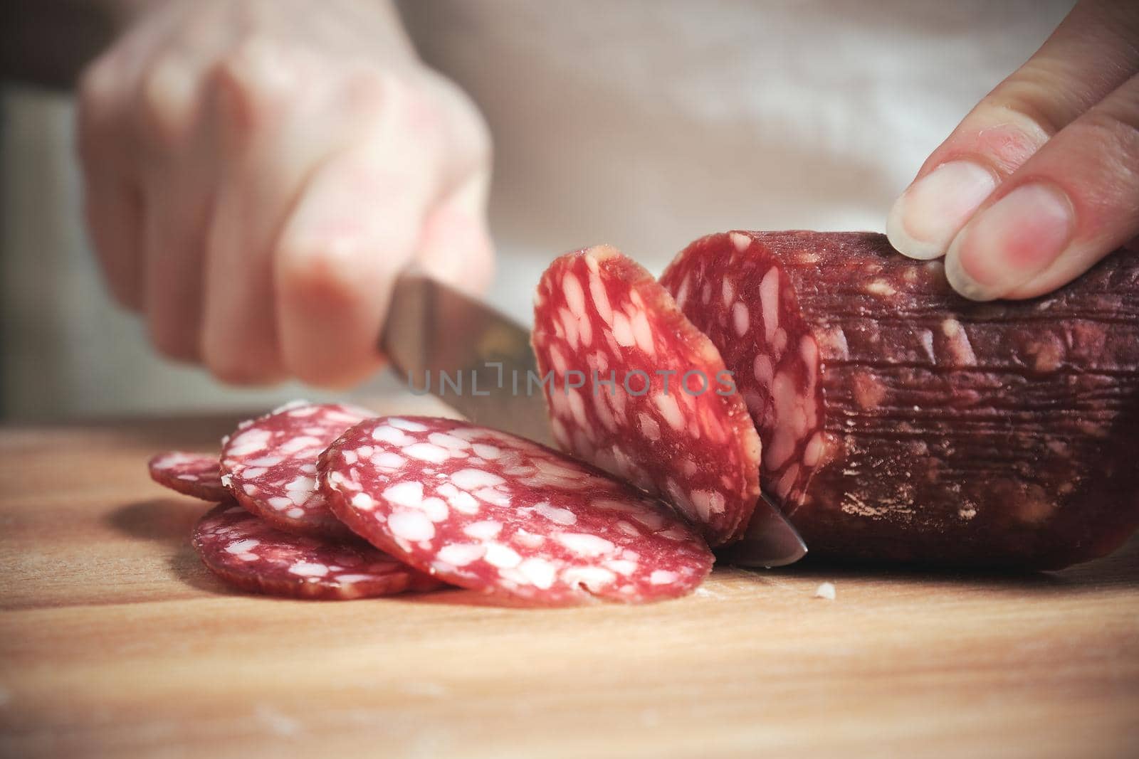 The knife cuts the smoked sausage into pieces