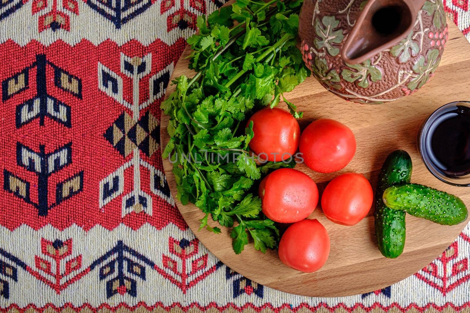 Tomatoes, cucumbers, herbs, a jug and wine on a wooden tray