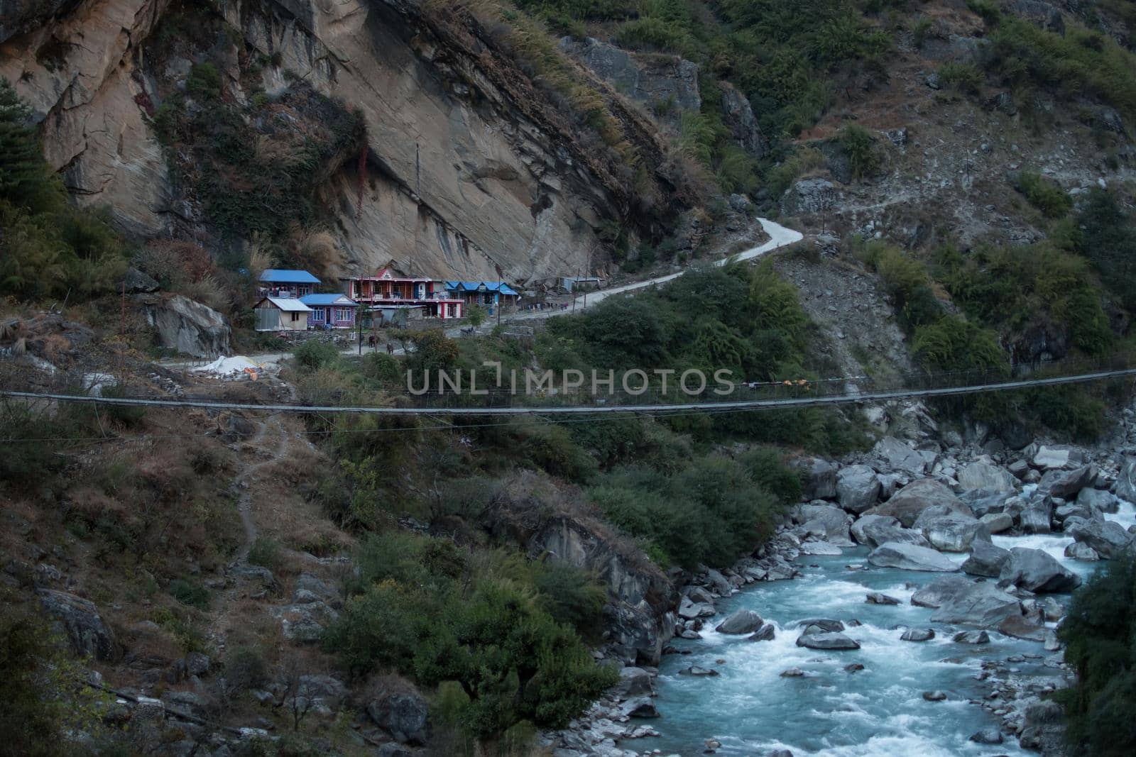 Nepalese mountain village by a suspension bridge over the Marshyangdi river gorge valley, Annapurna circuit, Himalaya, Nepal, Asia
