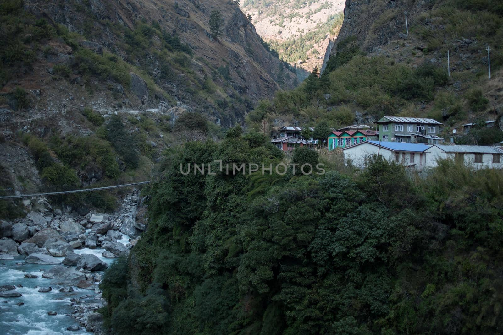 Nepalese mountain village by a suspension bridge over the Marshyangdi river by arvidnorberg