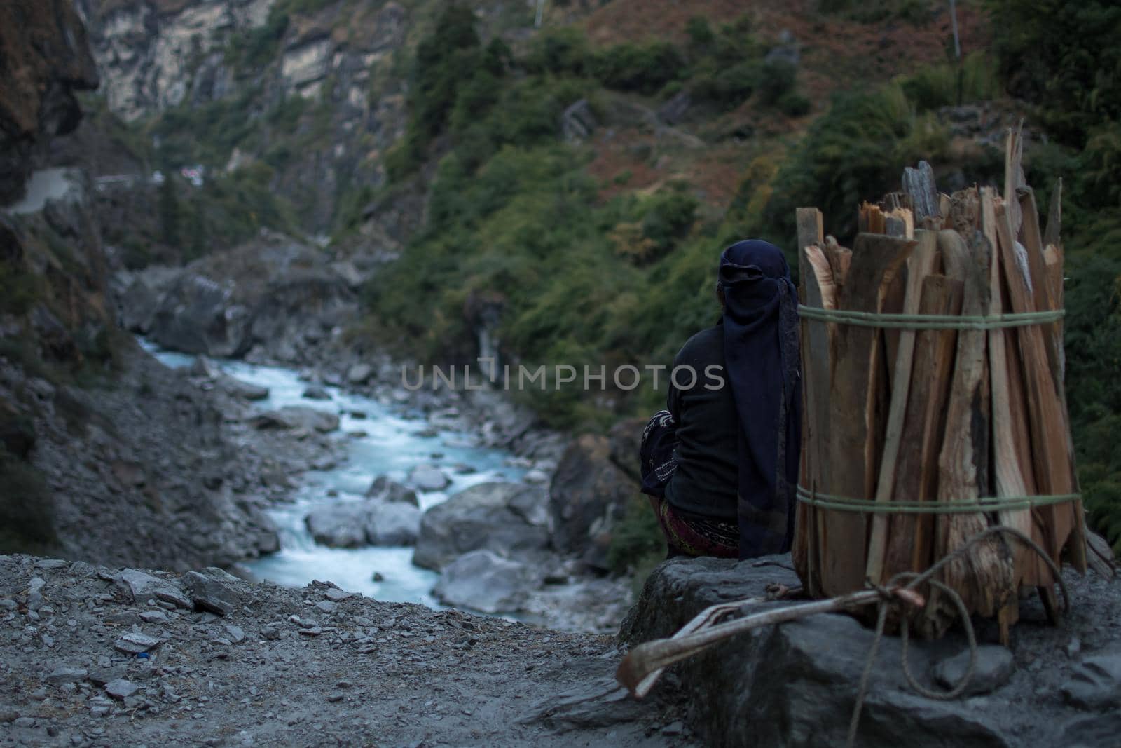 Strong working nepalese woman resting, sitting, looking at Marshyangdi river by arvidnorberg