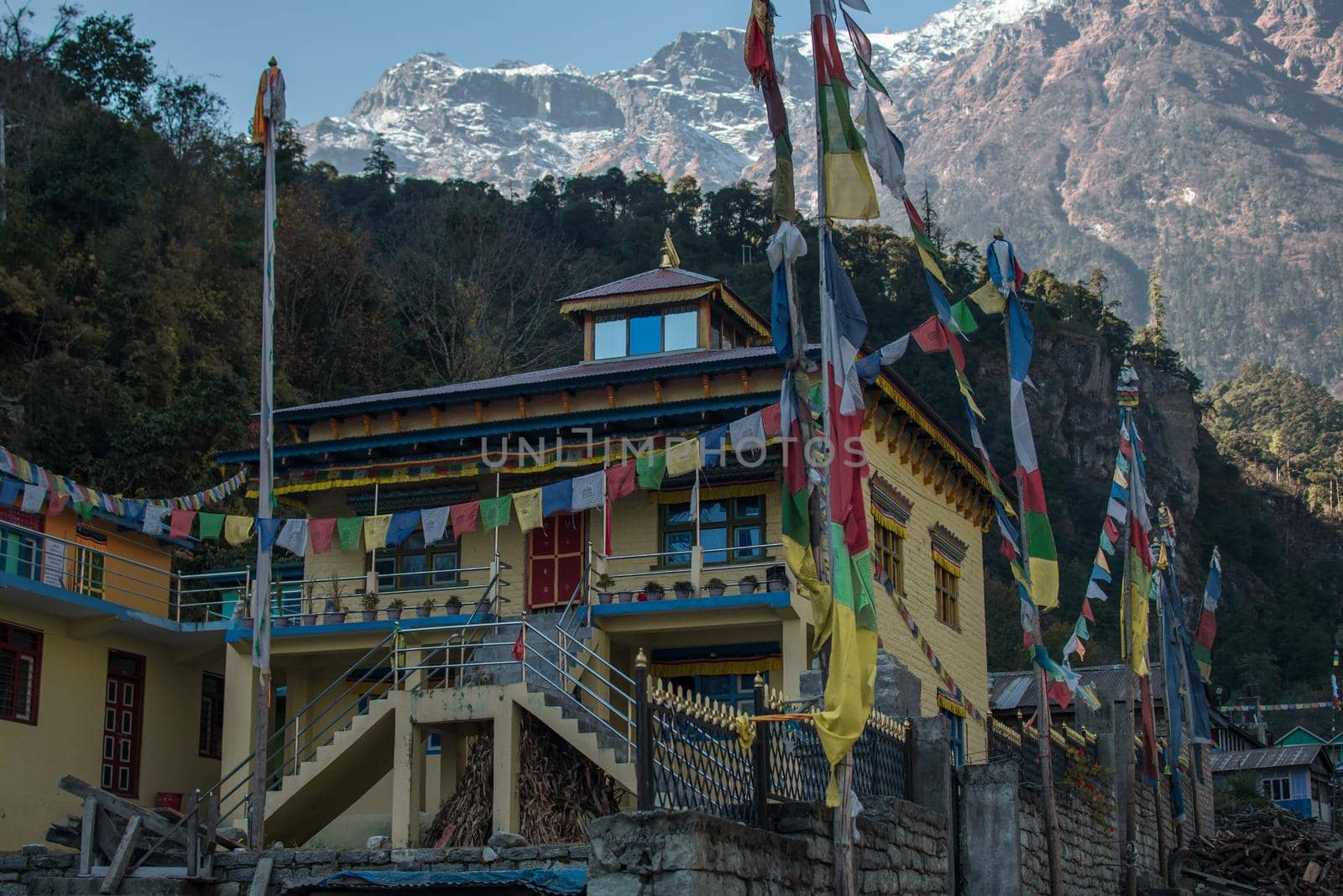 Yellow buddhist monastery with buddhist prayer flags, underneath himalayan mountains along Annapurna circuit