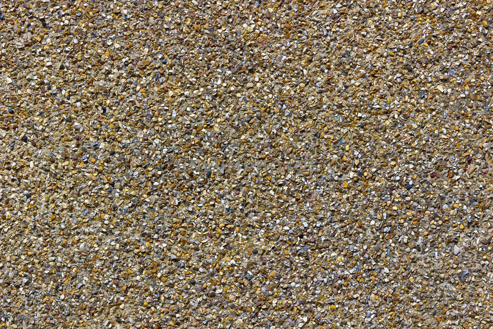 A rough pebble dash covering on an external wall showing small stones of various shapes and colours