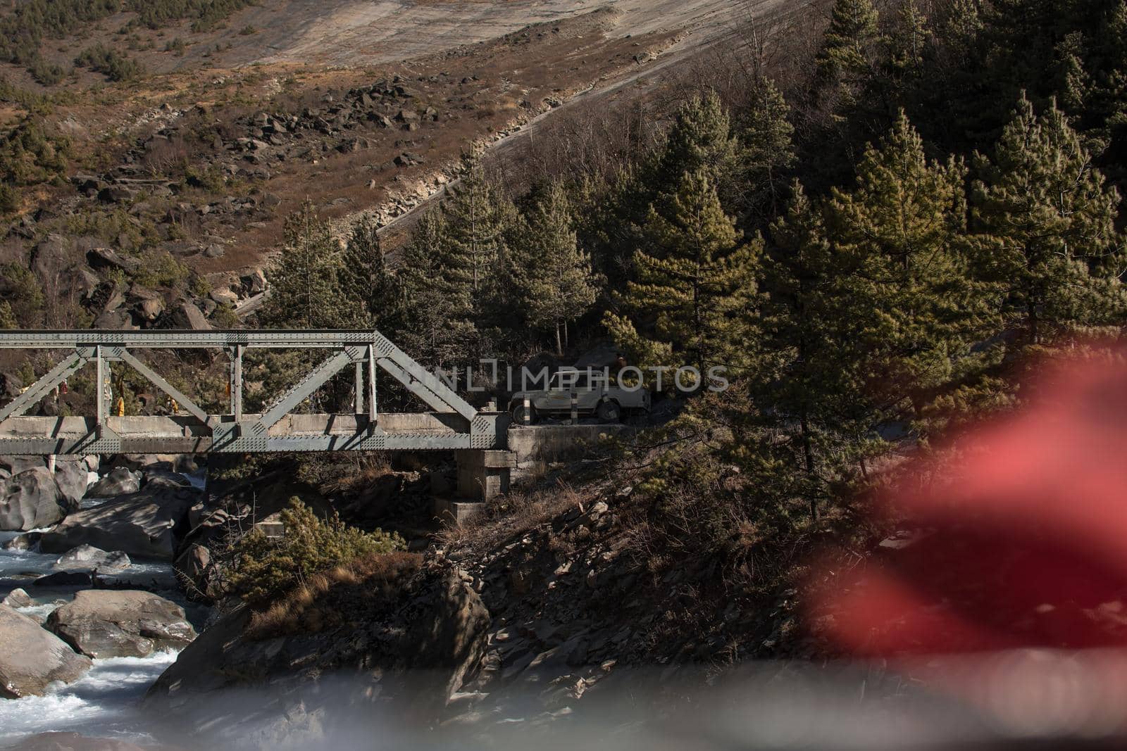 White car driving over a bridge in a forest on a mountain