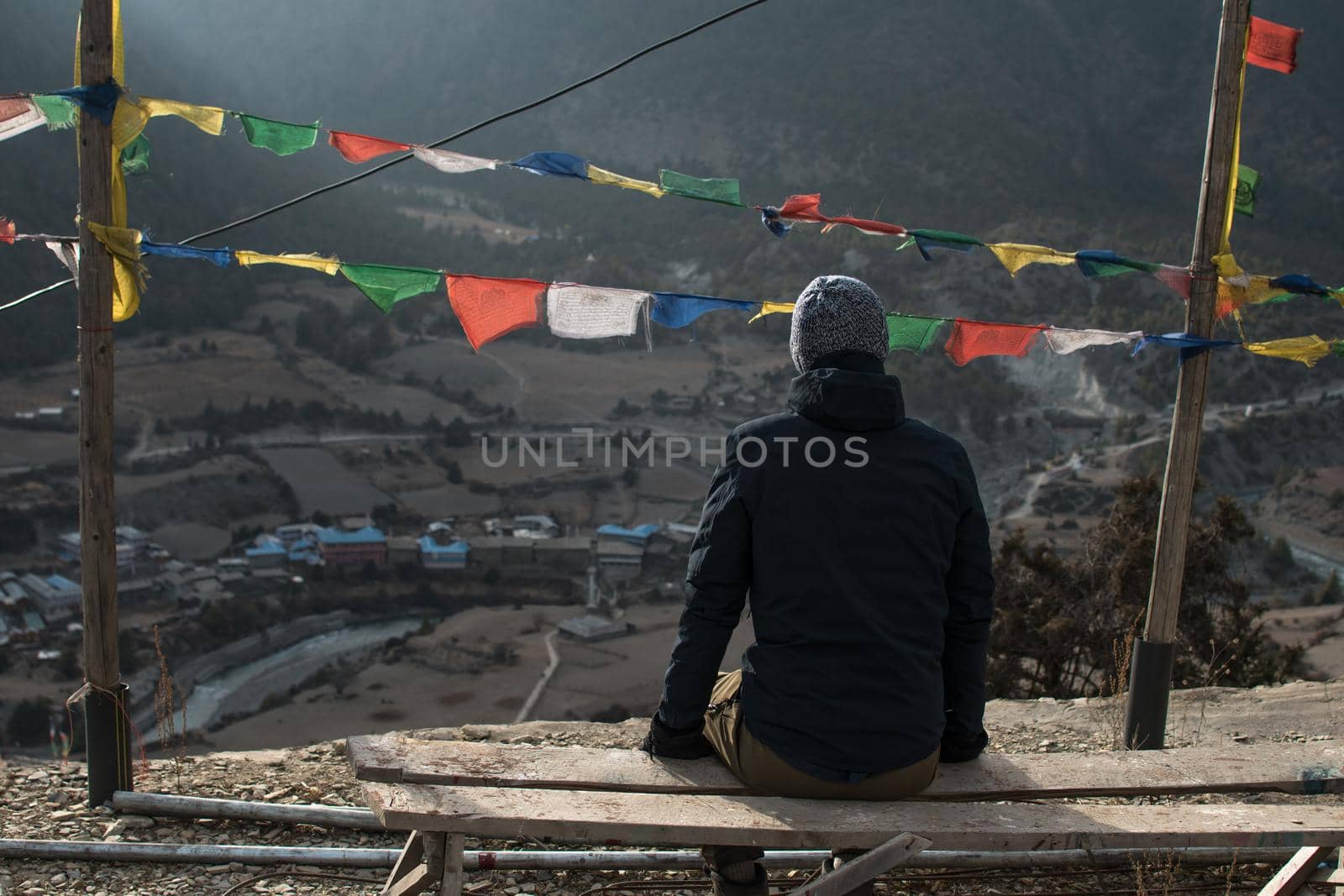 Young man looking over Lower Pisang mountain village, trekking Annapurna circuit, Himalaya, Nepal