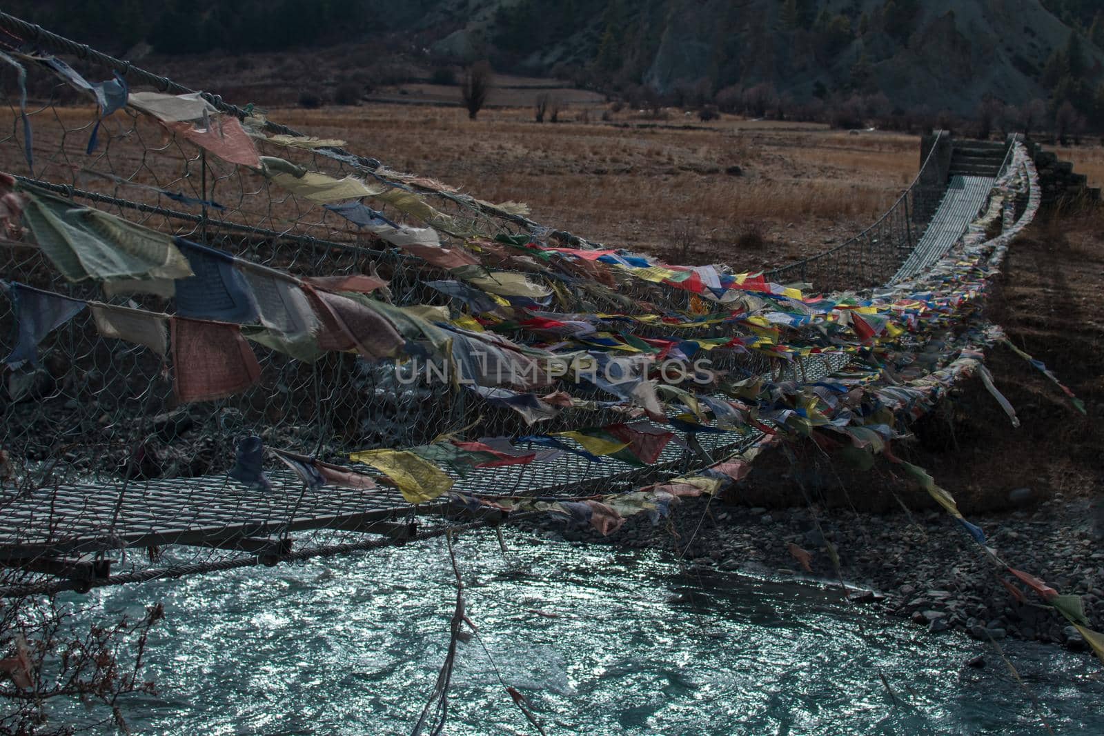 Walkway suspension bridge with buddhist colorful prayer flags blowinn in the wind