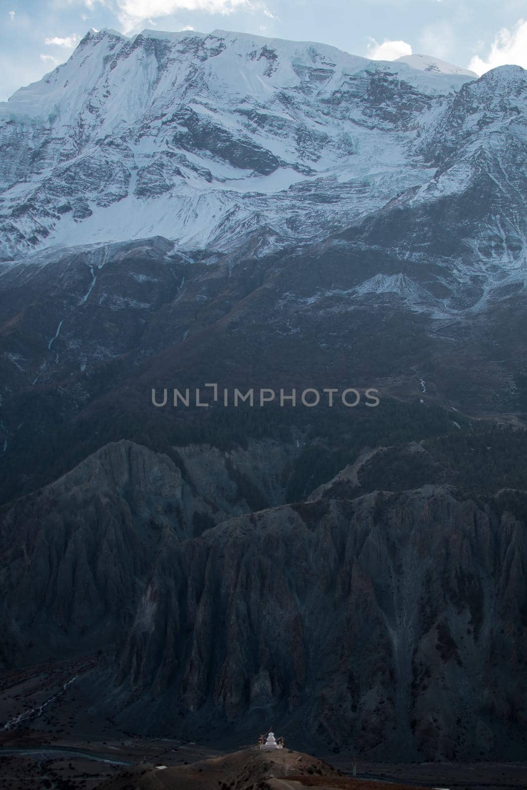 Buddhist stupa with prayer flags in front of massive mountain by arvidnorberg