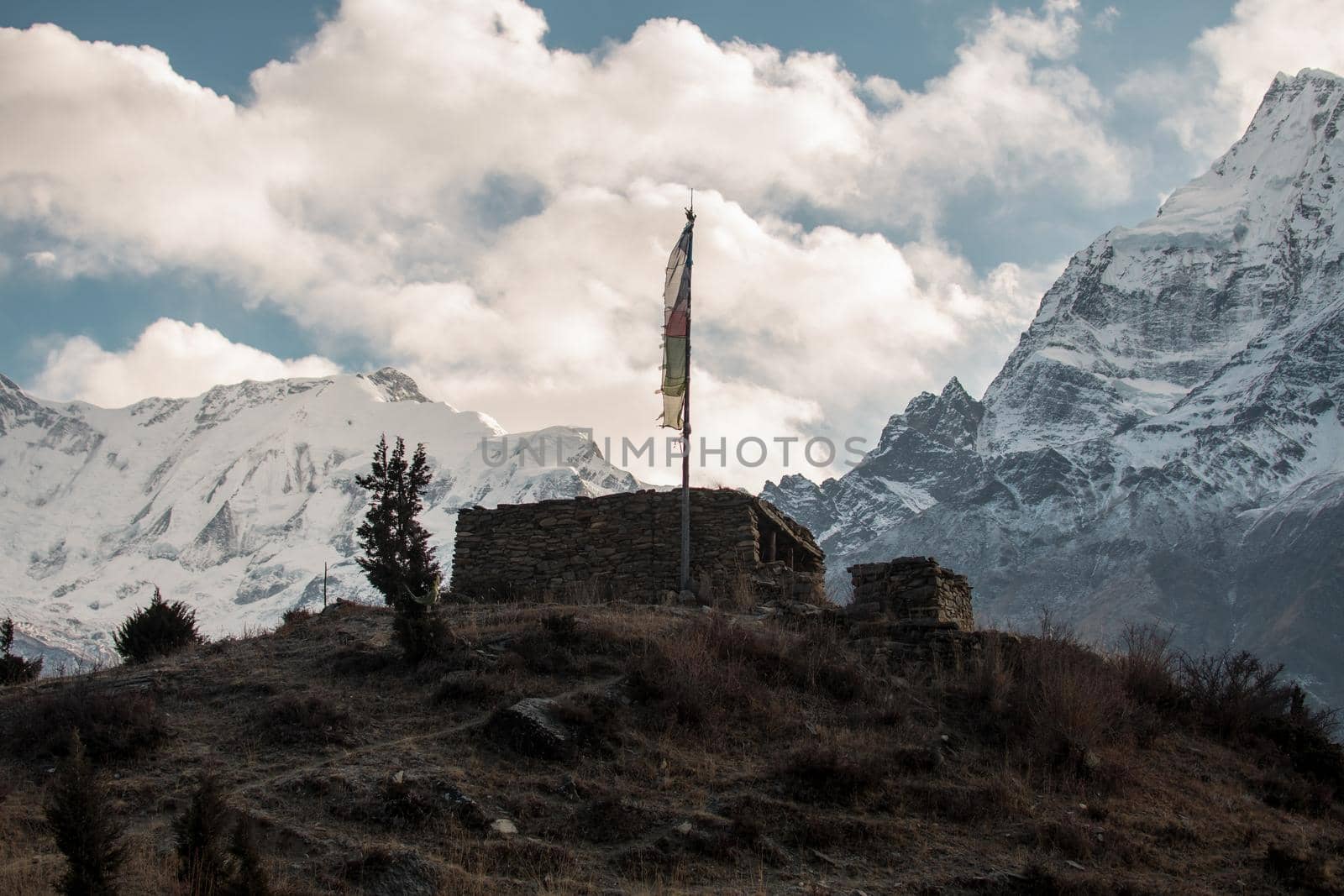 Buddhist stone building with prayer flags over Manang mountain village, trekking Annapurna circuit, Nepal