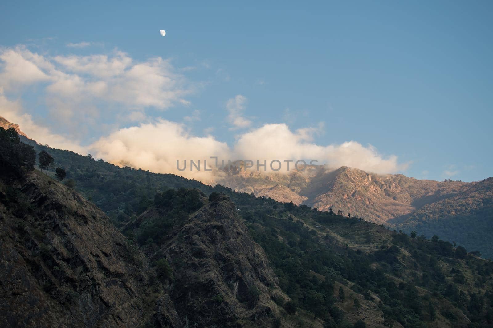Beautiful scenery with the moon over mountain peaks during the day