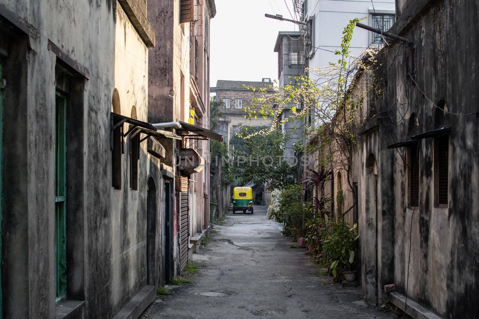 Kolkata, India - February 1, 2020: A yellow and green cng tuk tuk is parked in an alley in between recitential buildings on December 1, 2020 in Kolkata, India