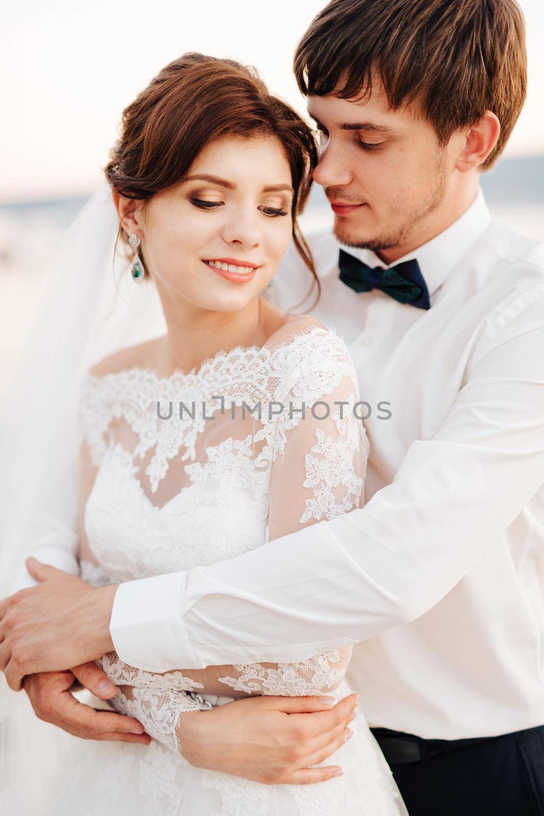 the groom gently hugs the bride from behind. High quality photo