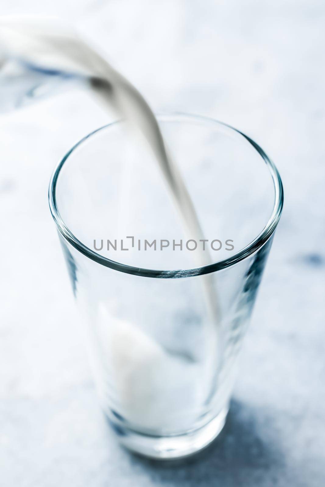 Dairy, healthy nutrition and breakfast concept - World Milk Day, pouring into glass on marble table