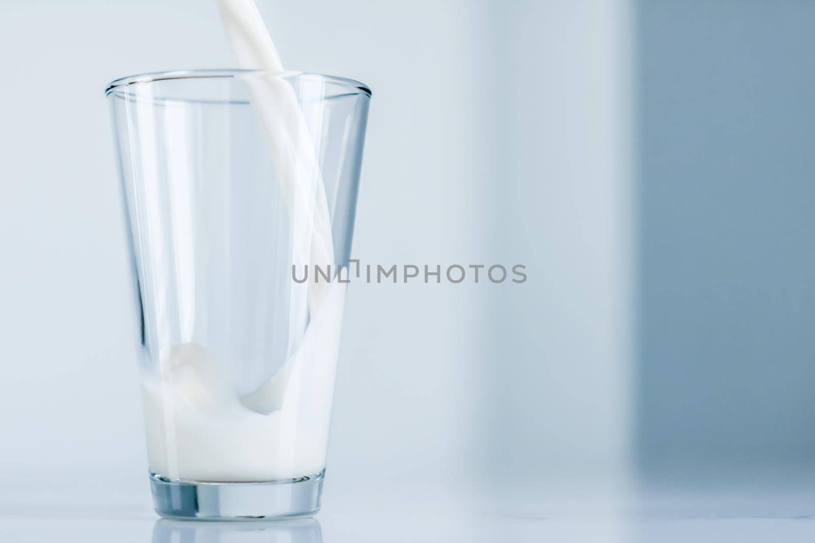 Dairy, healthy nutrition and breakfast concept - World Milk Day, pouring into glass on marble table