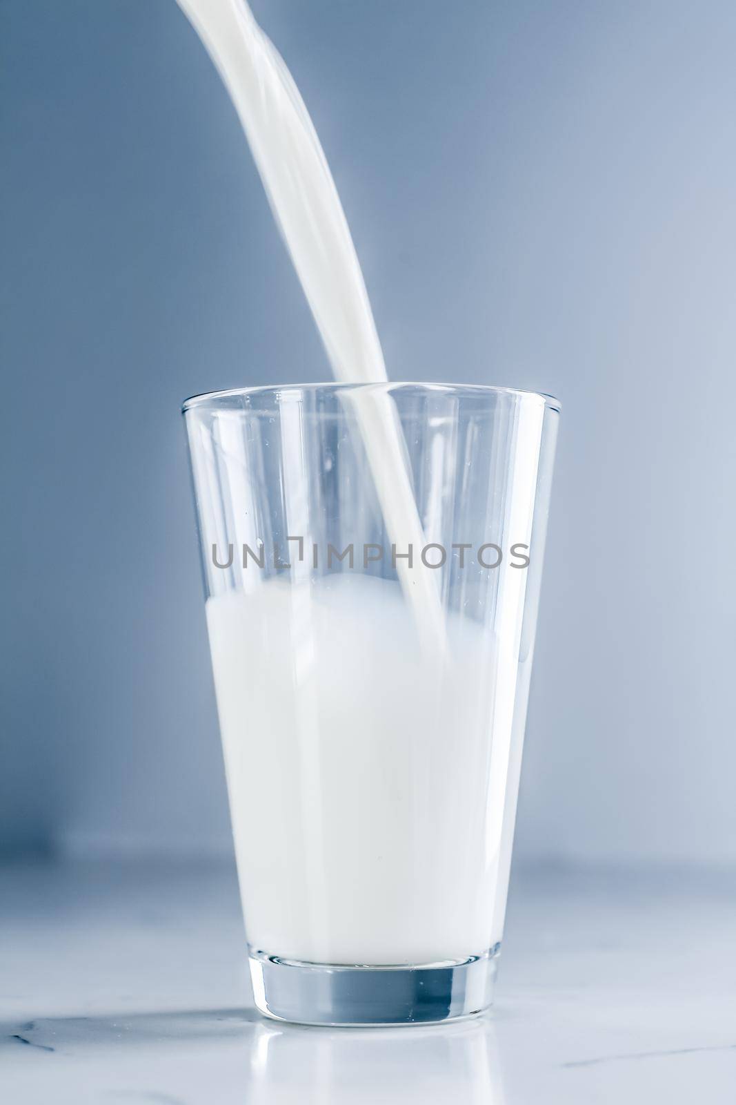 Dairy, healthy nutrition and breakfast concept - World Milk Day, pouring into glass on marble table