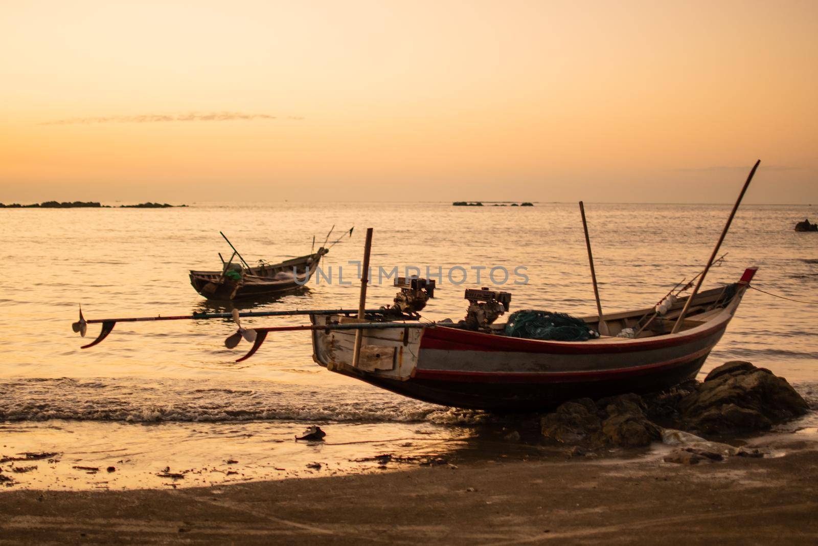 Two traditional wooden boats in a bright orange sunset, Ngwesaung, Myanmar by arvidnorberg