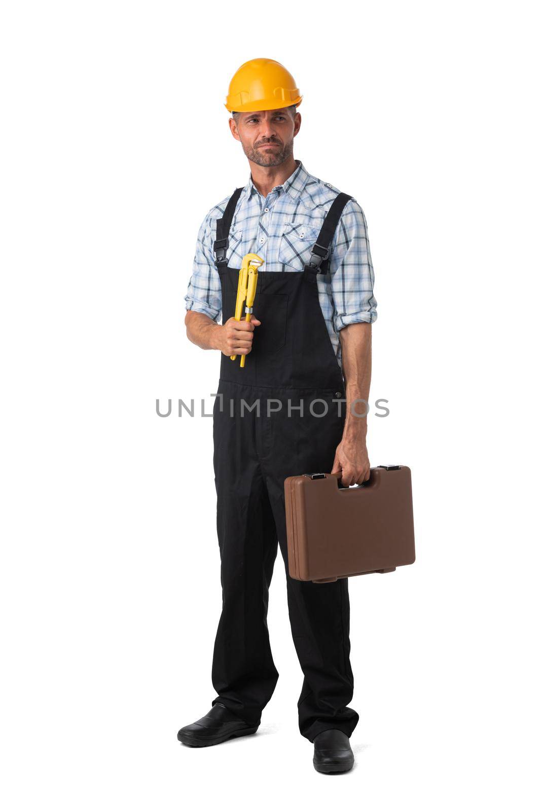 Full length portrait of confident male repairman contractor worker in coveralls holding adjustable spanner and toolbox on white background