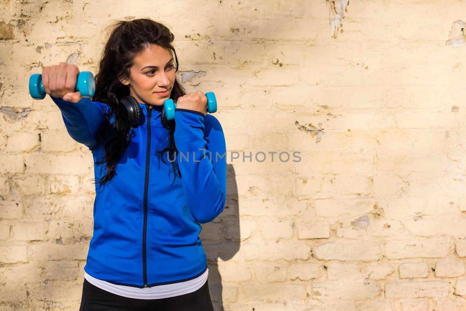 Beautiful woman exercising  with weights outdoor.