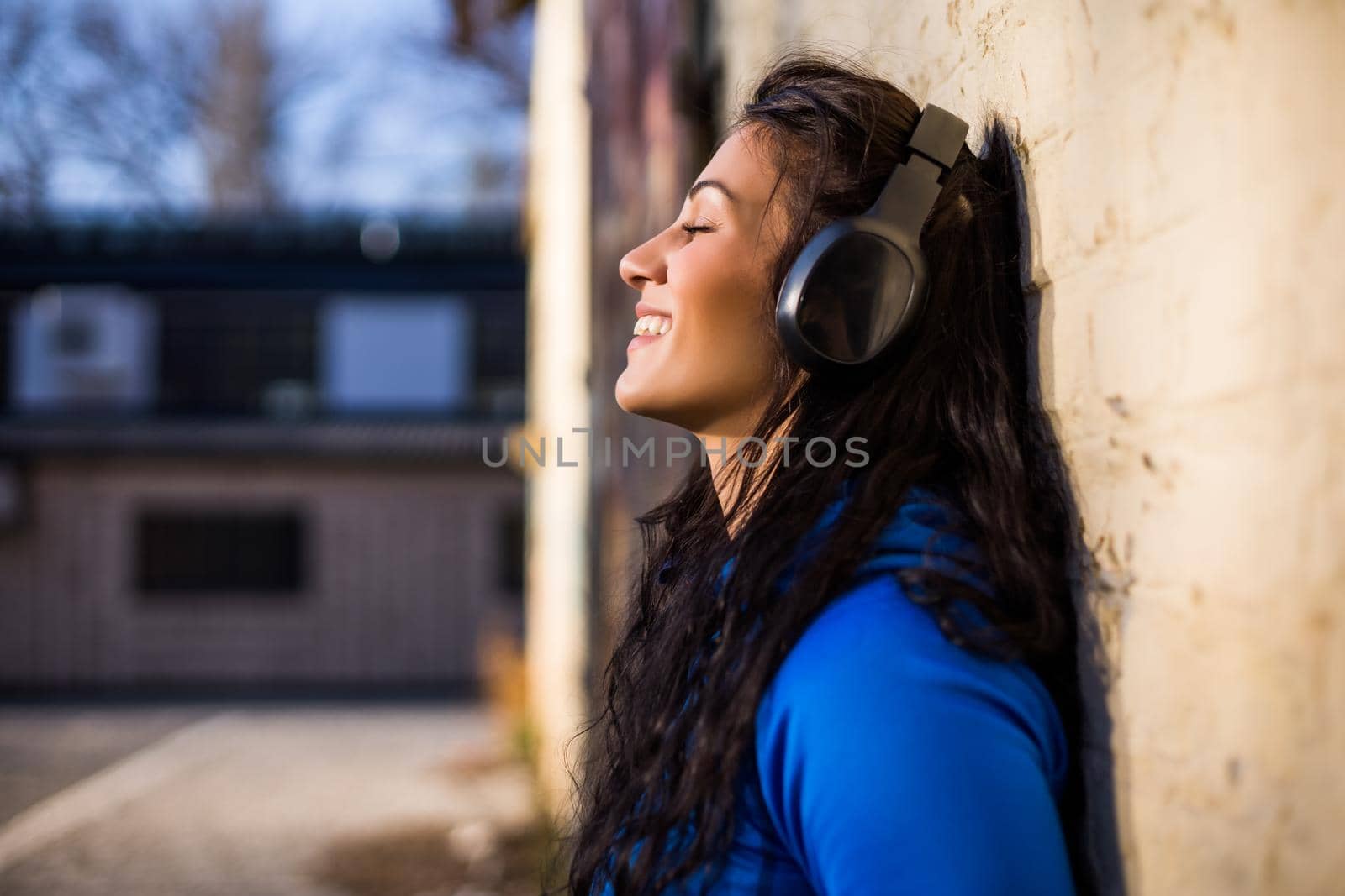 Beautiful sporty woman with headphones  enjoys listening music outdoor.