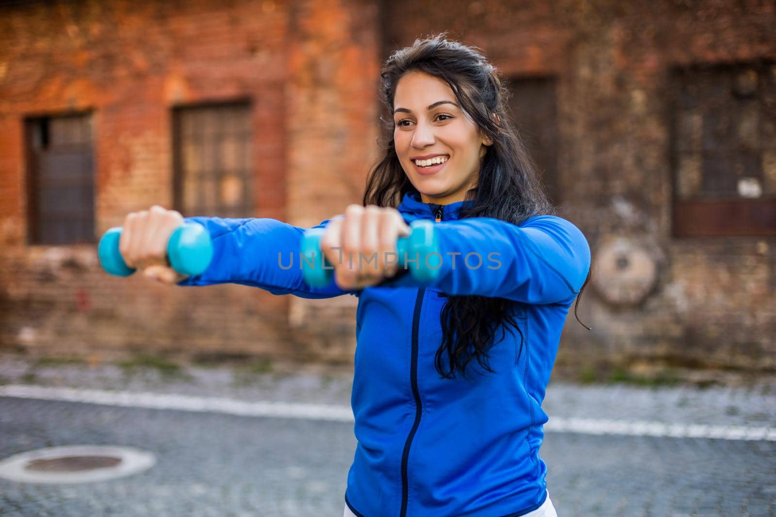 Woman exercising outdoor with weights by Bazdar