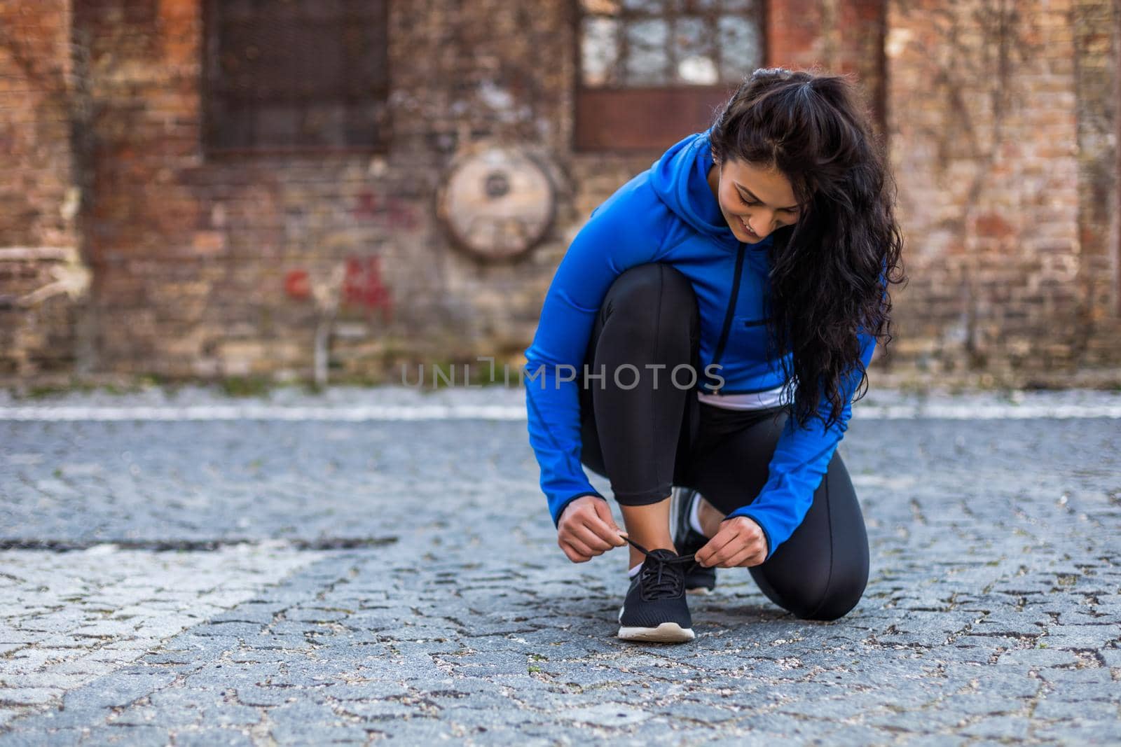 Beautiful young sporty woman is tying shoelace outdoor.