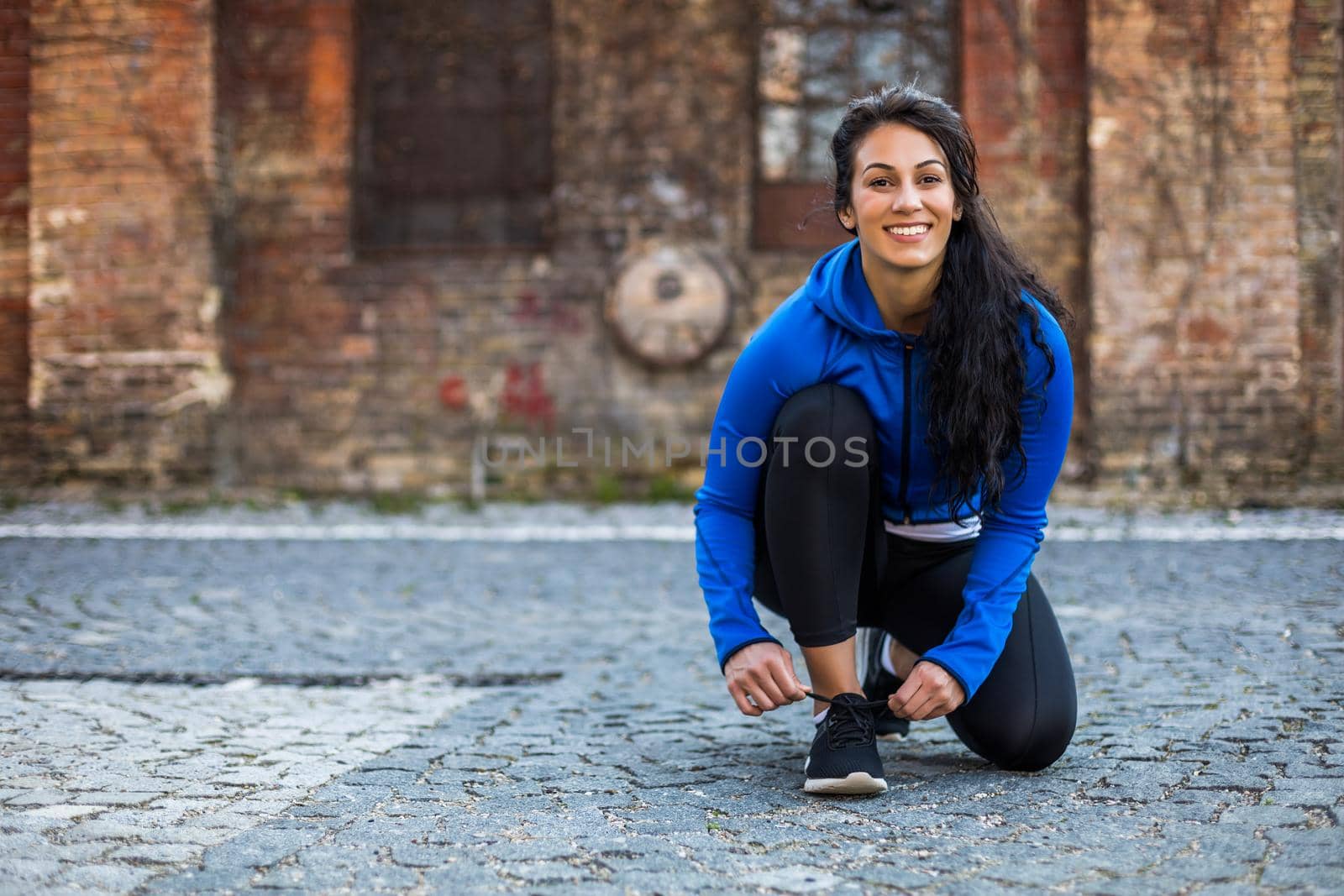 Sporty woman is tying shoelace by Bazdar